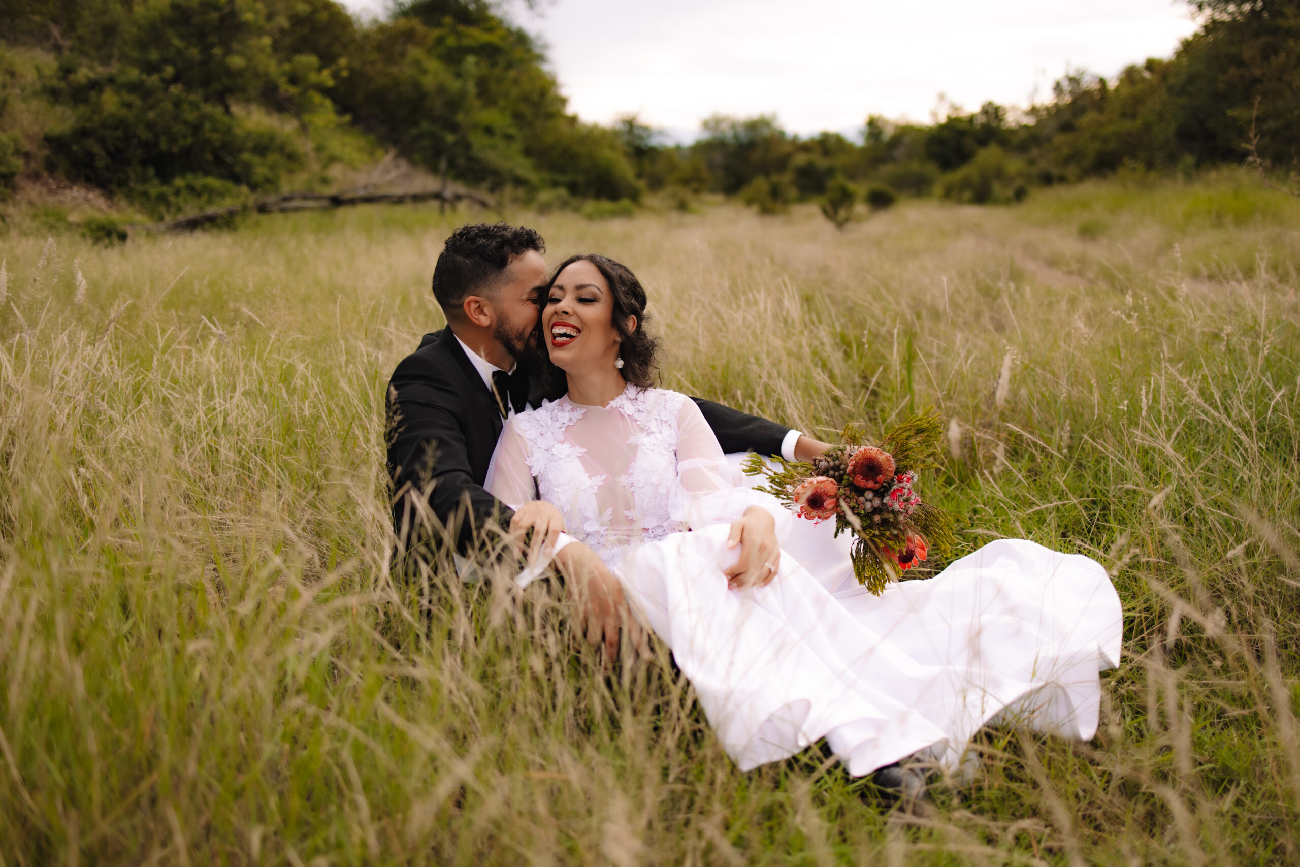 Safari wedding couple sitting between the long green grass in Kruger National Park