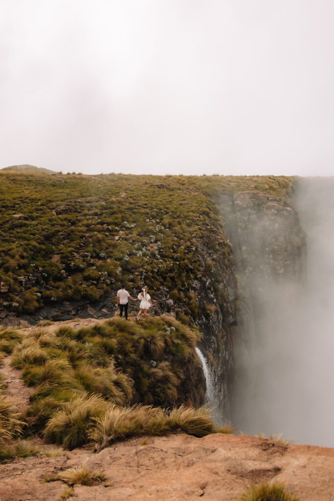 An elopement couple walking towards the edge of the highest waterfall in South Africa called Tugela Falls