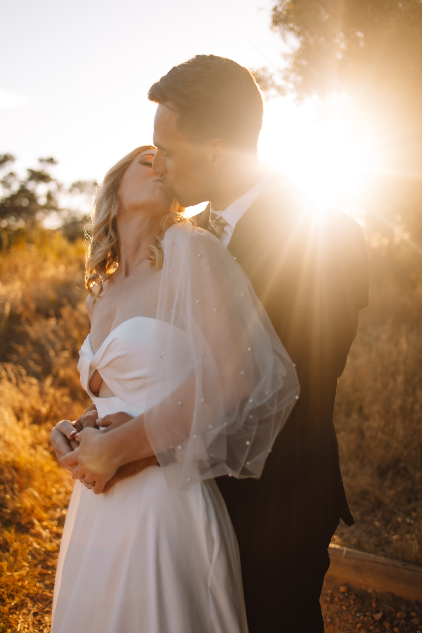 Bride in a white strapless wedding  and groom kissing during sunset during their South Africa elopement