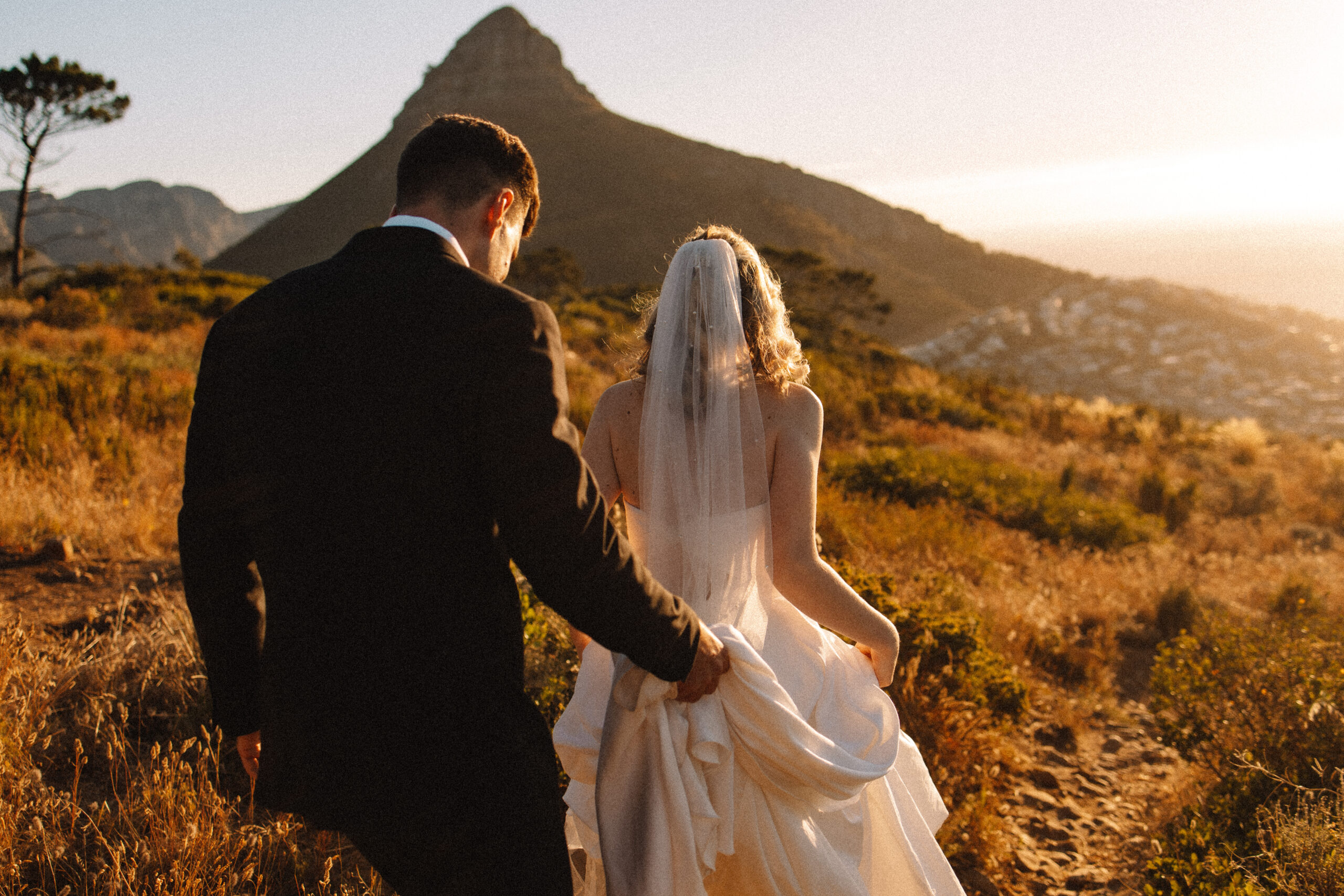 Bride in a white strapless wedding  and groom walking in a field during their South Africa elopement