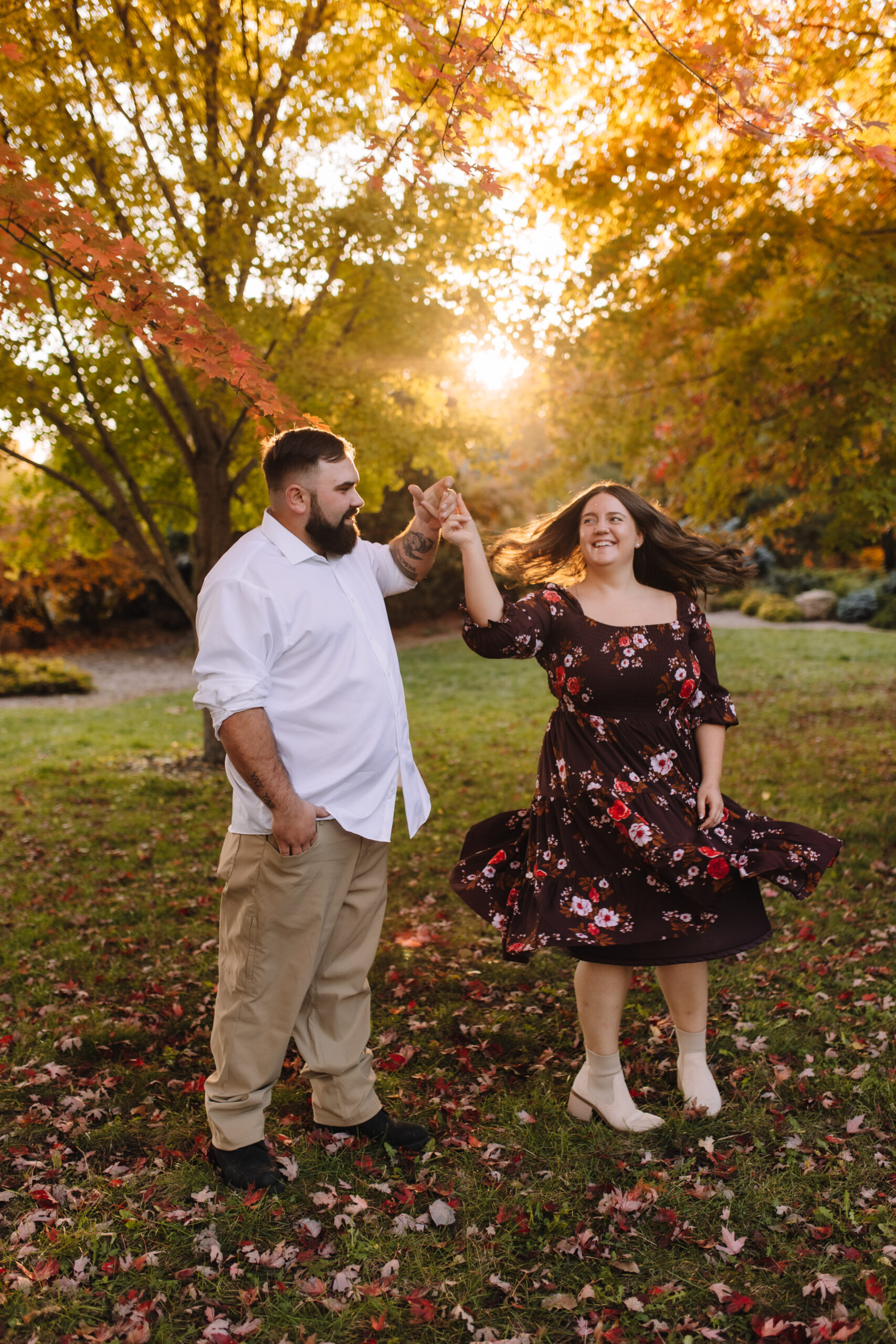 Newly engaged couple dancing holding hands wearing spring engagement outfits