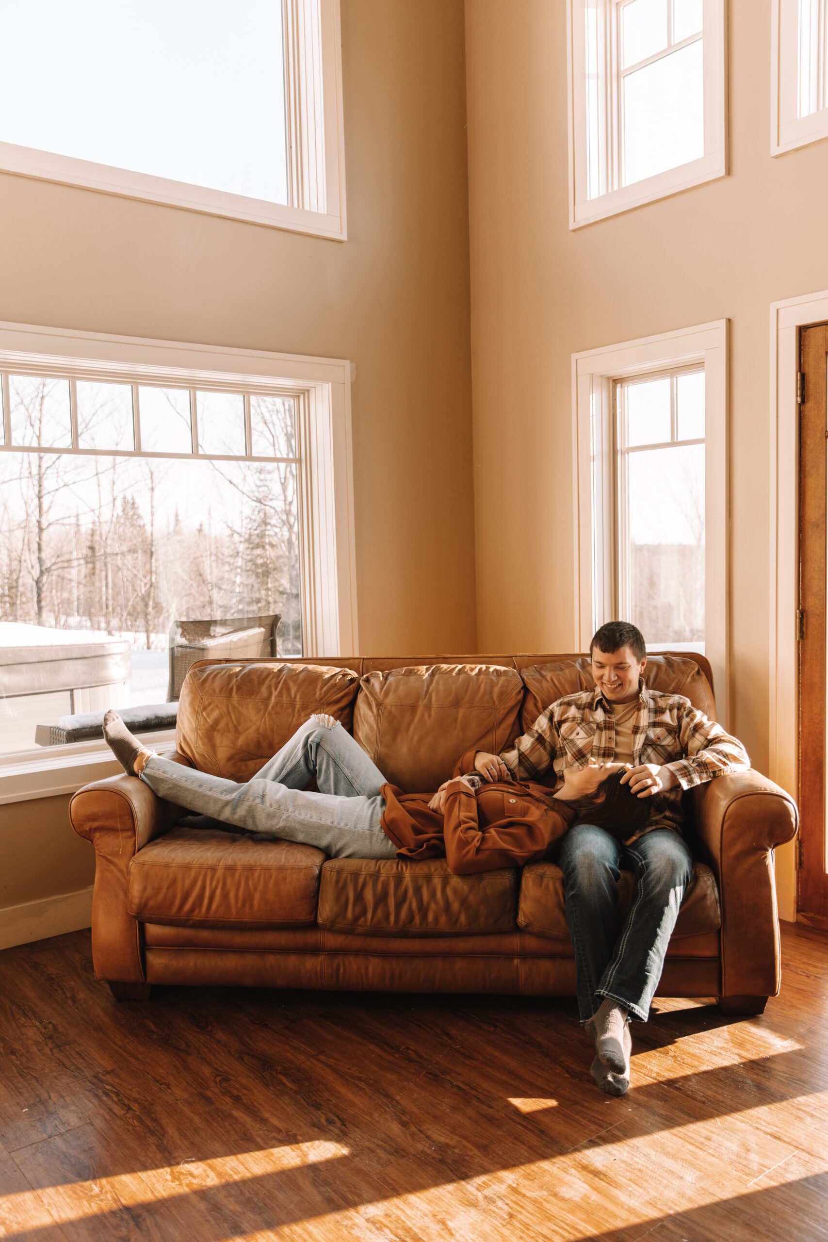 Newly engaged couple sitting together on a couch relaxing for their engagement shoot