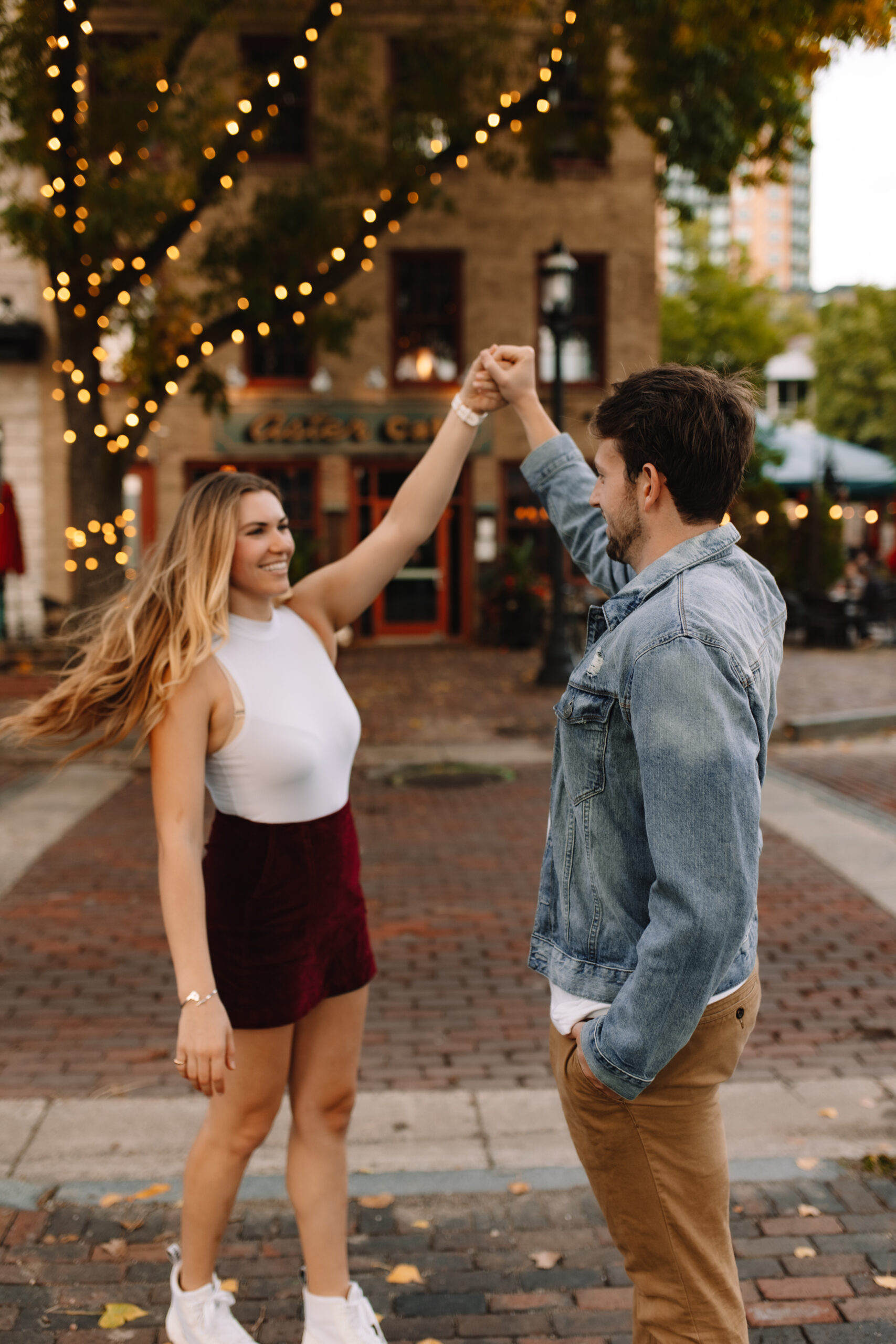 Newly engaged couple dancing on cobblestone streets in Minnesota