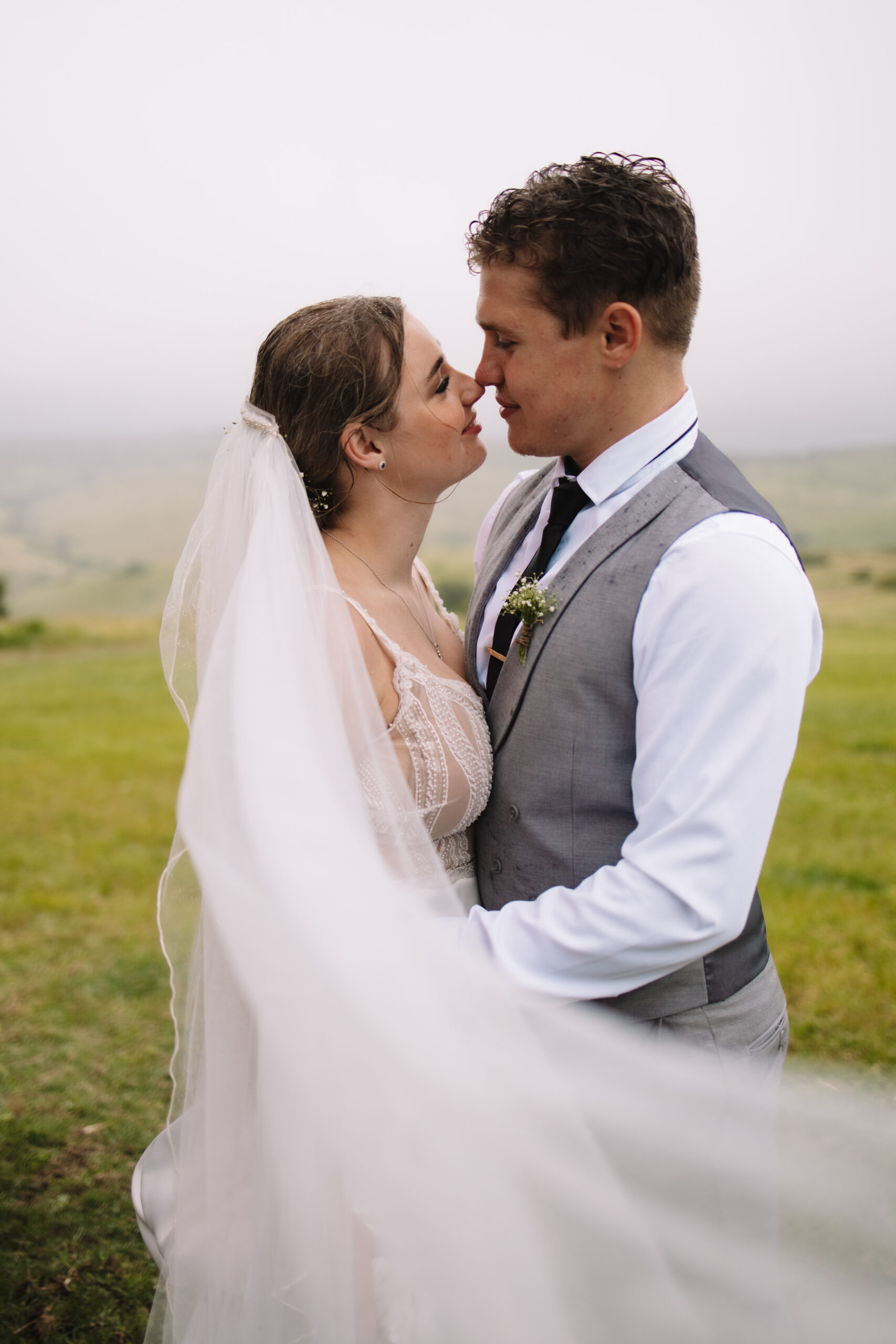 Bride and groom staring into eachother eyes in a field of grass