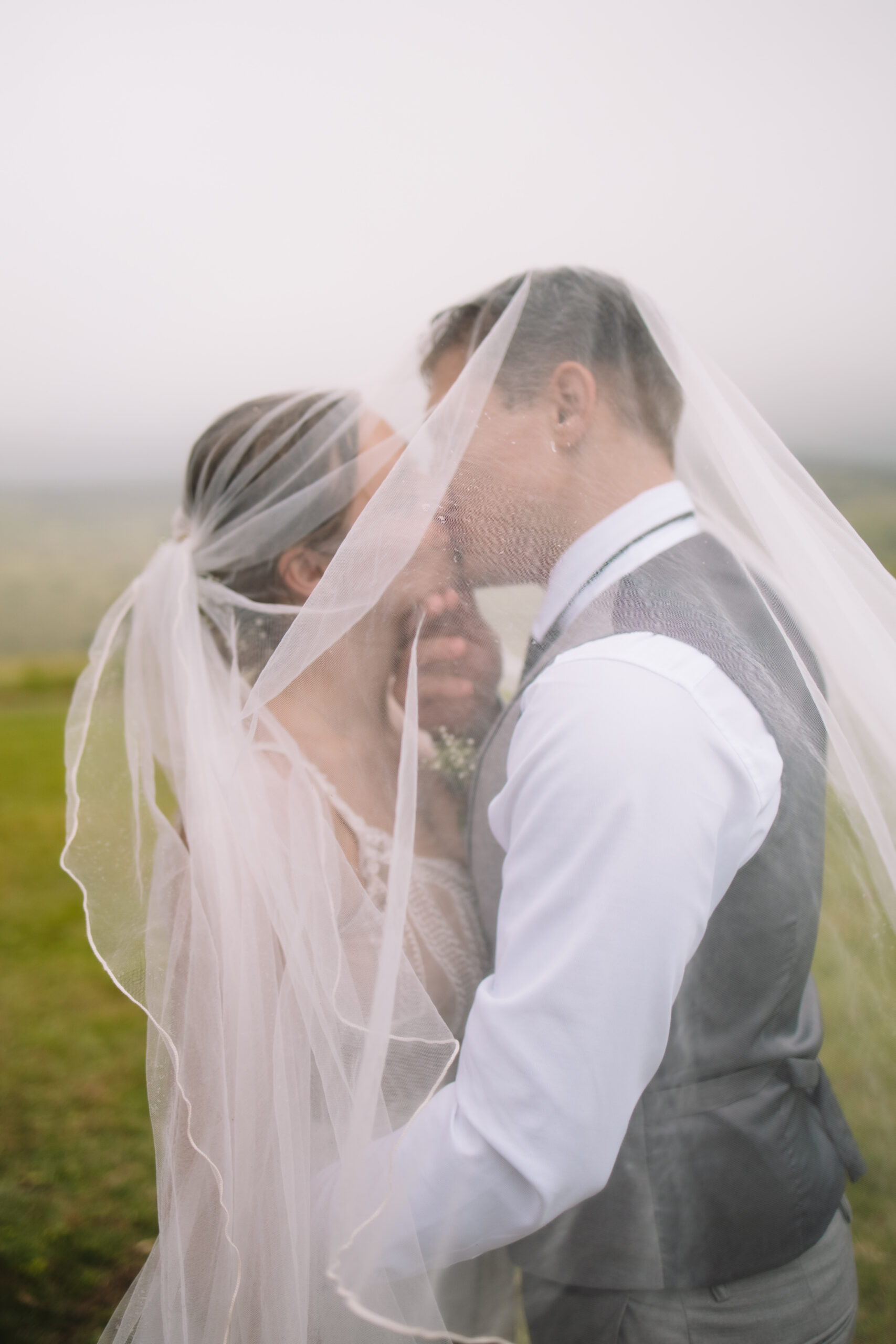 Bride and groom kissing under brides veil