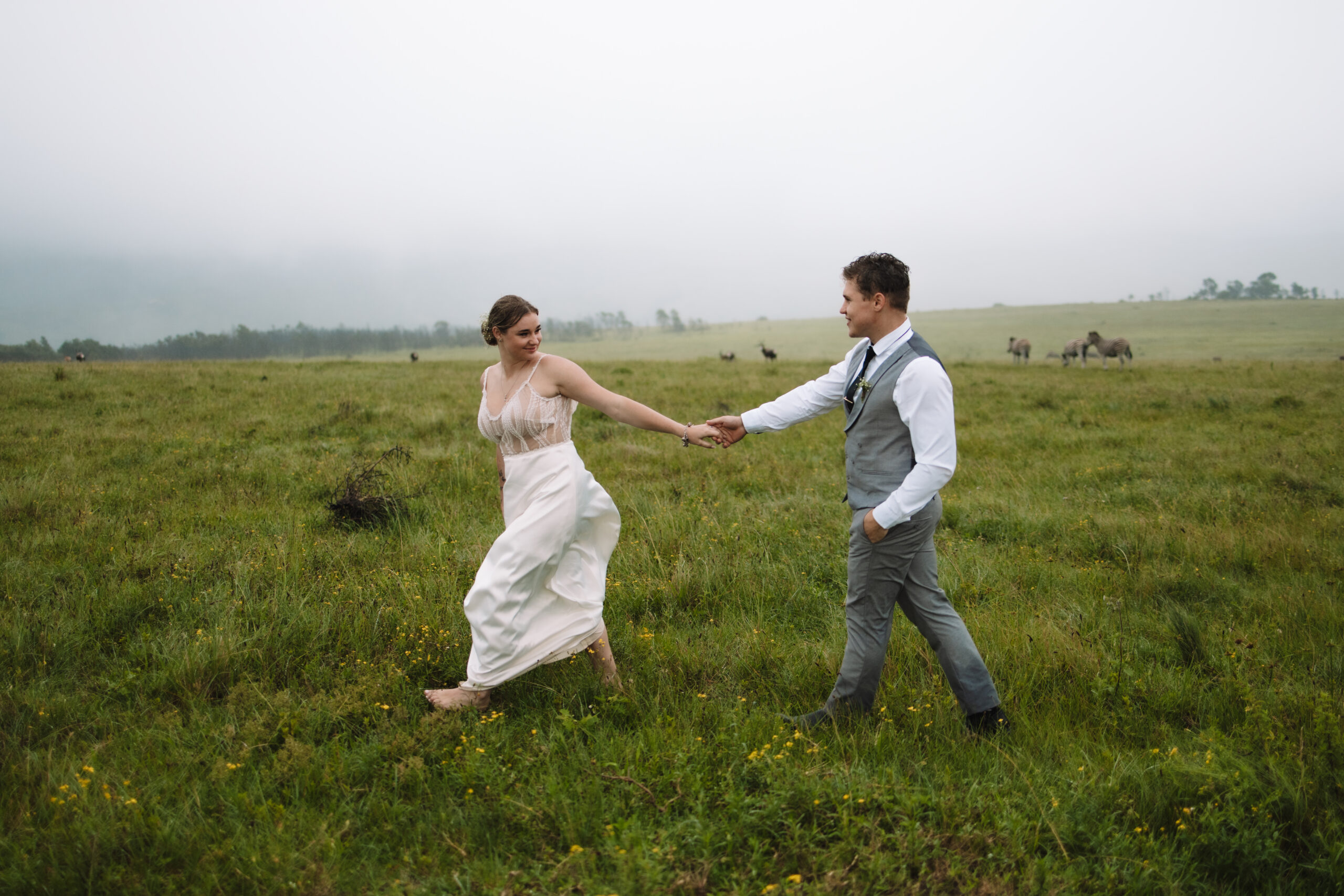 Bride and groom walking in a field of grass during their destination wedding in South Africa 