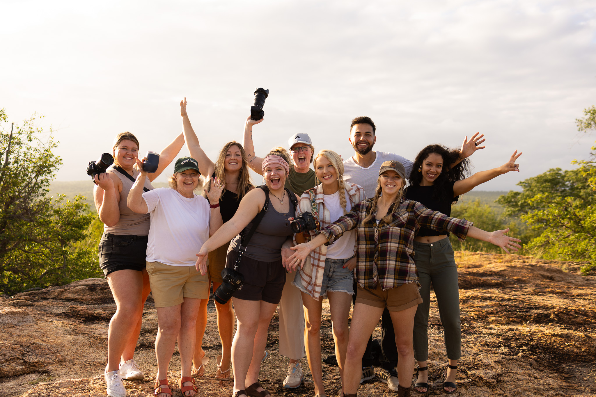 A group of destination wedding photographers during a photography content retreat in South Africa, standing together in a group smiling and cheering, lifting their hands in the air