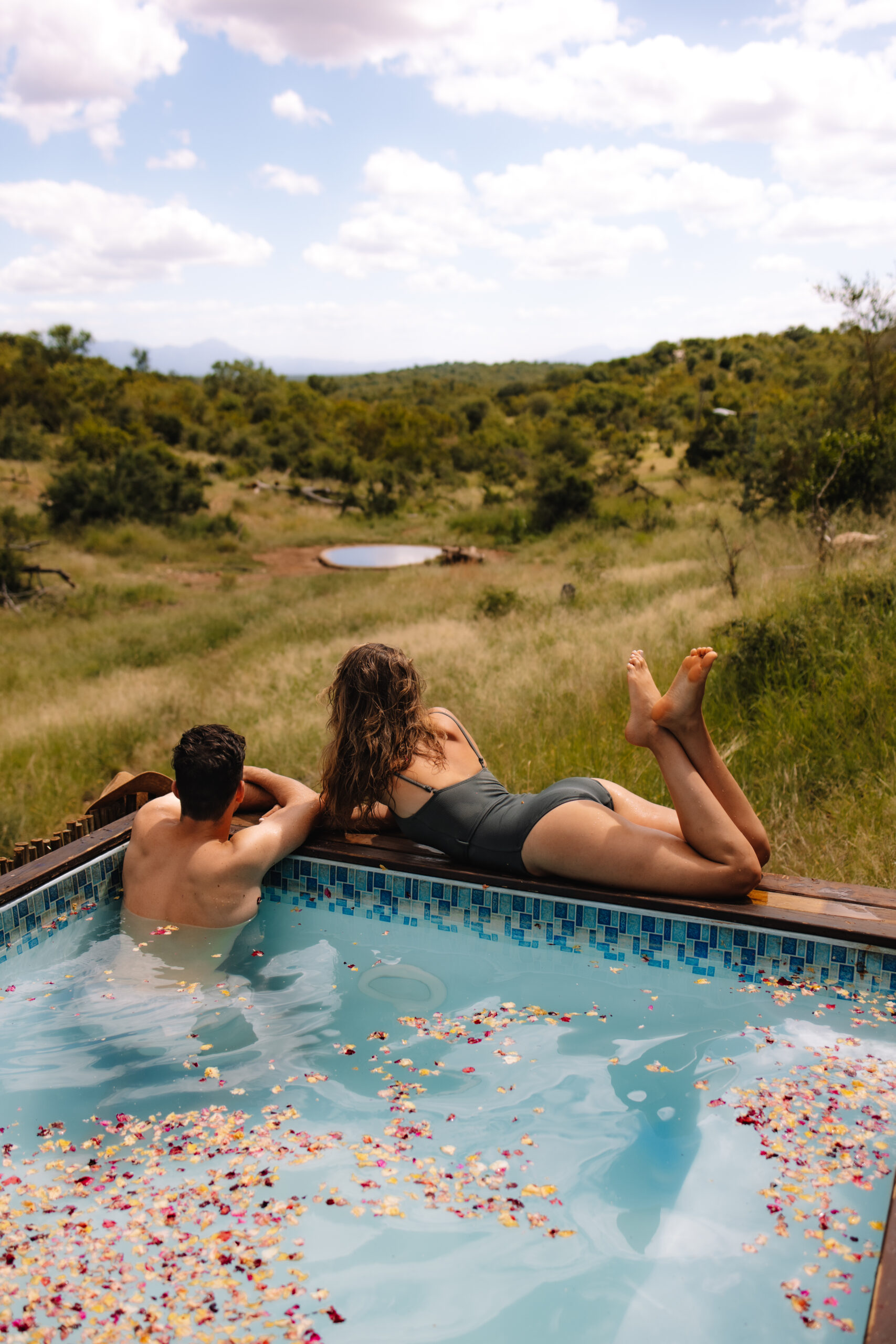 A model couple relaxing by the pool, filled with flowers, during a photography content retreat in South Africa