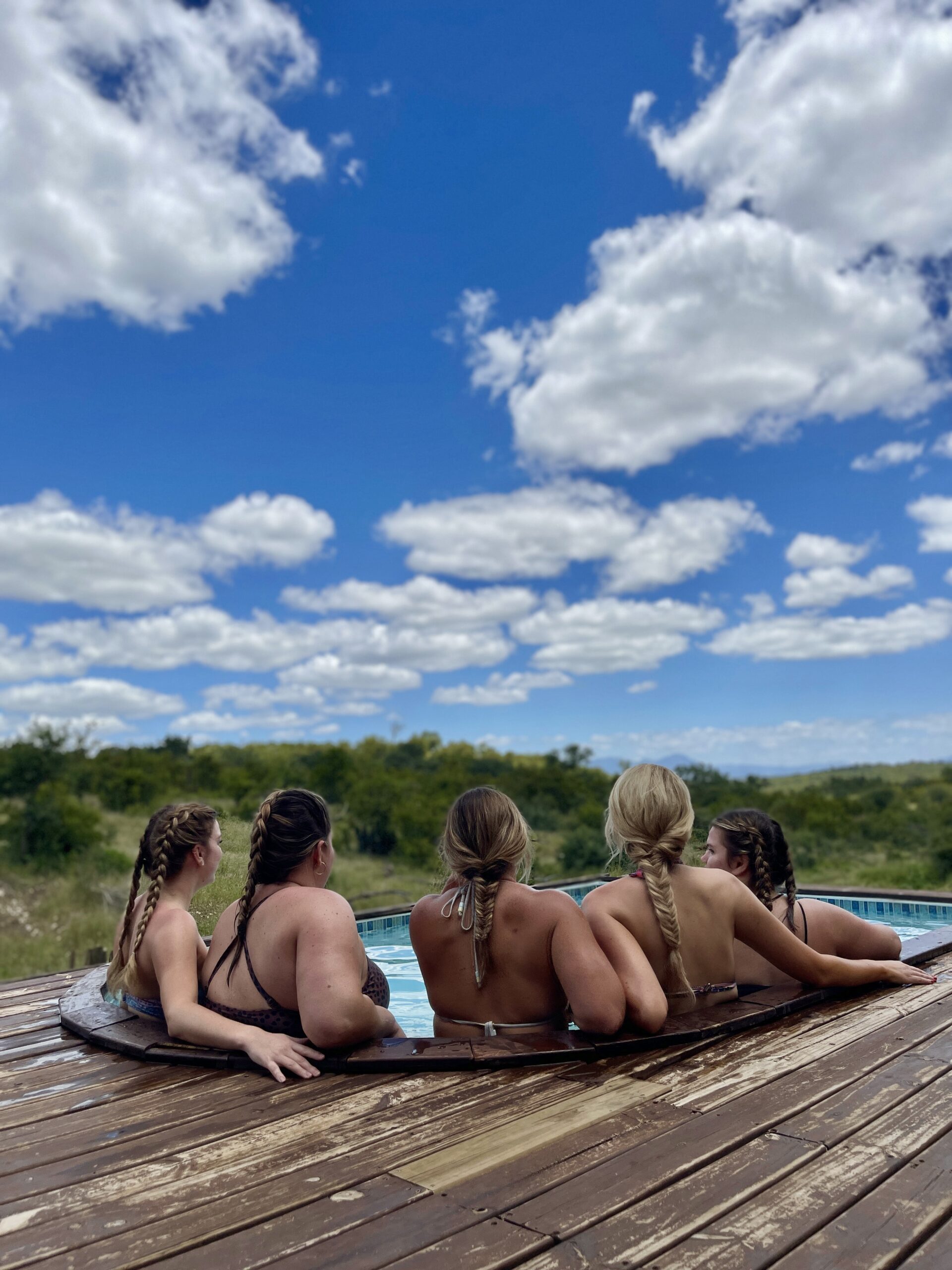 Photographers relaxing in a pool overlooking the bush while on a photography content retreat hosted by Heidi Straus Photography during her photography content retreats in Africa