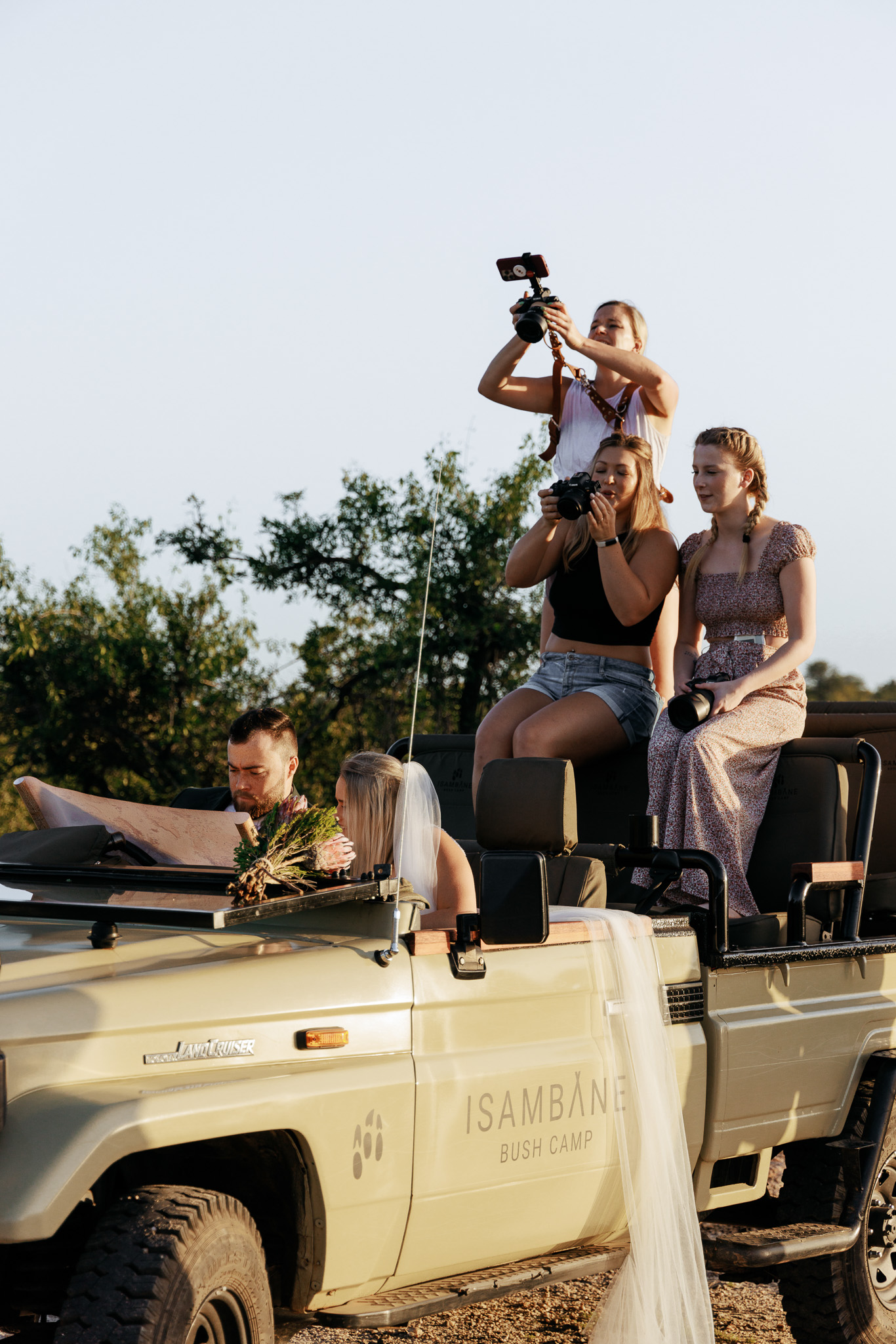 Photographers standing on a safari vehicle taking photos of a model couple during their photography content retreats in South Africa