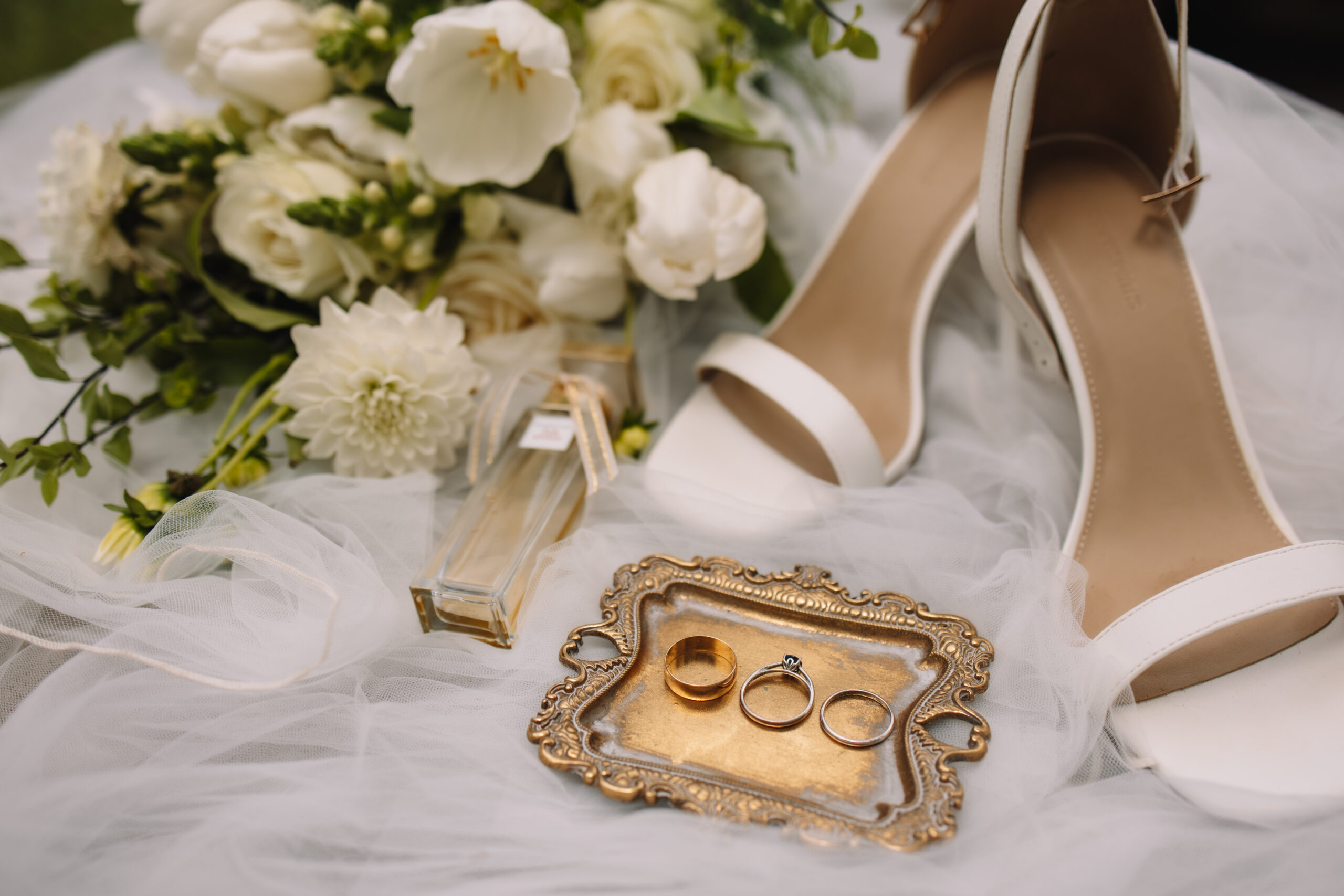 Simple Wedding flat lay details of bride's veil, white shoes, rings, perfume and bouquet