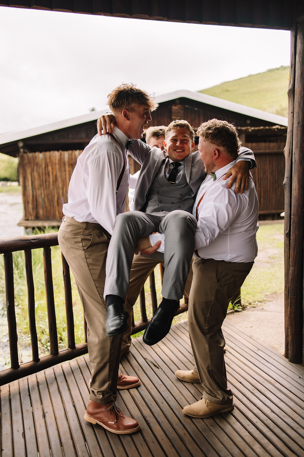 Groomsmen picking up groom acting silly for photos