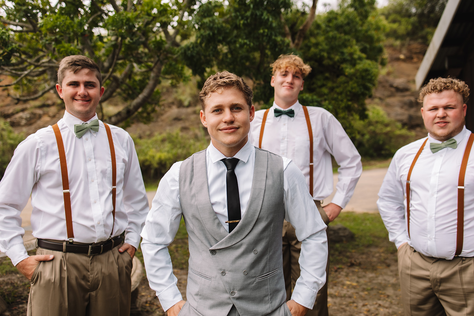 Groom and groomsmen posing for a photo in tuxes and overalls