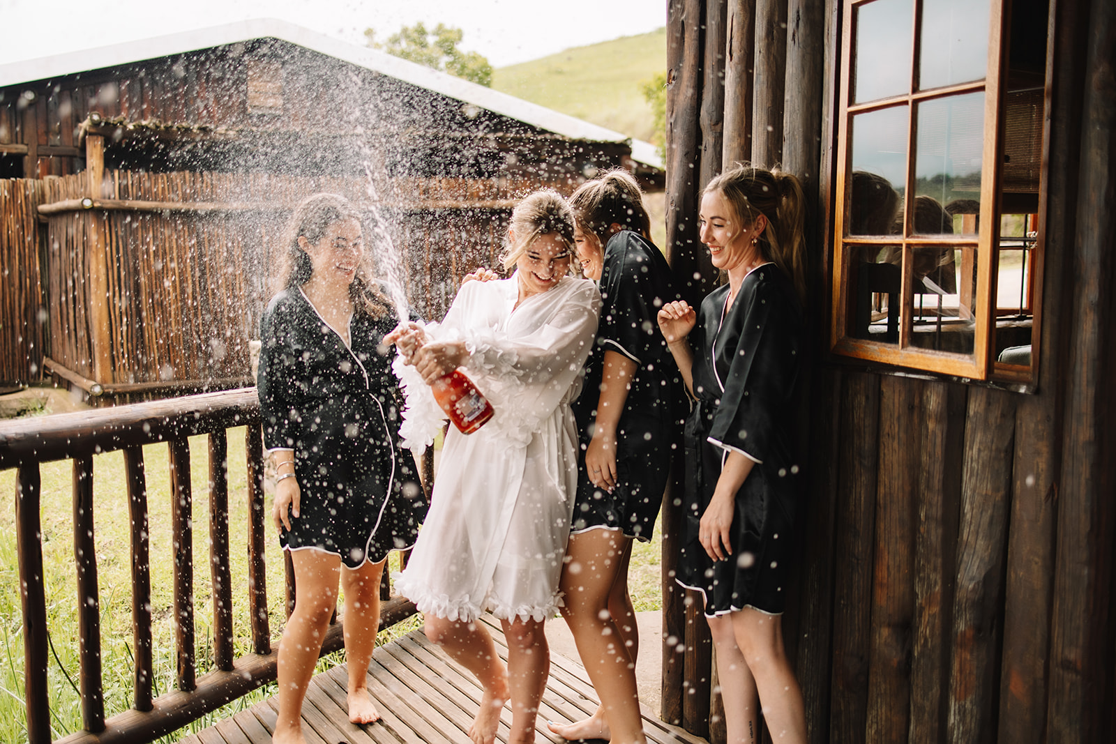 Bride popping champagne with her bridesmaids