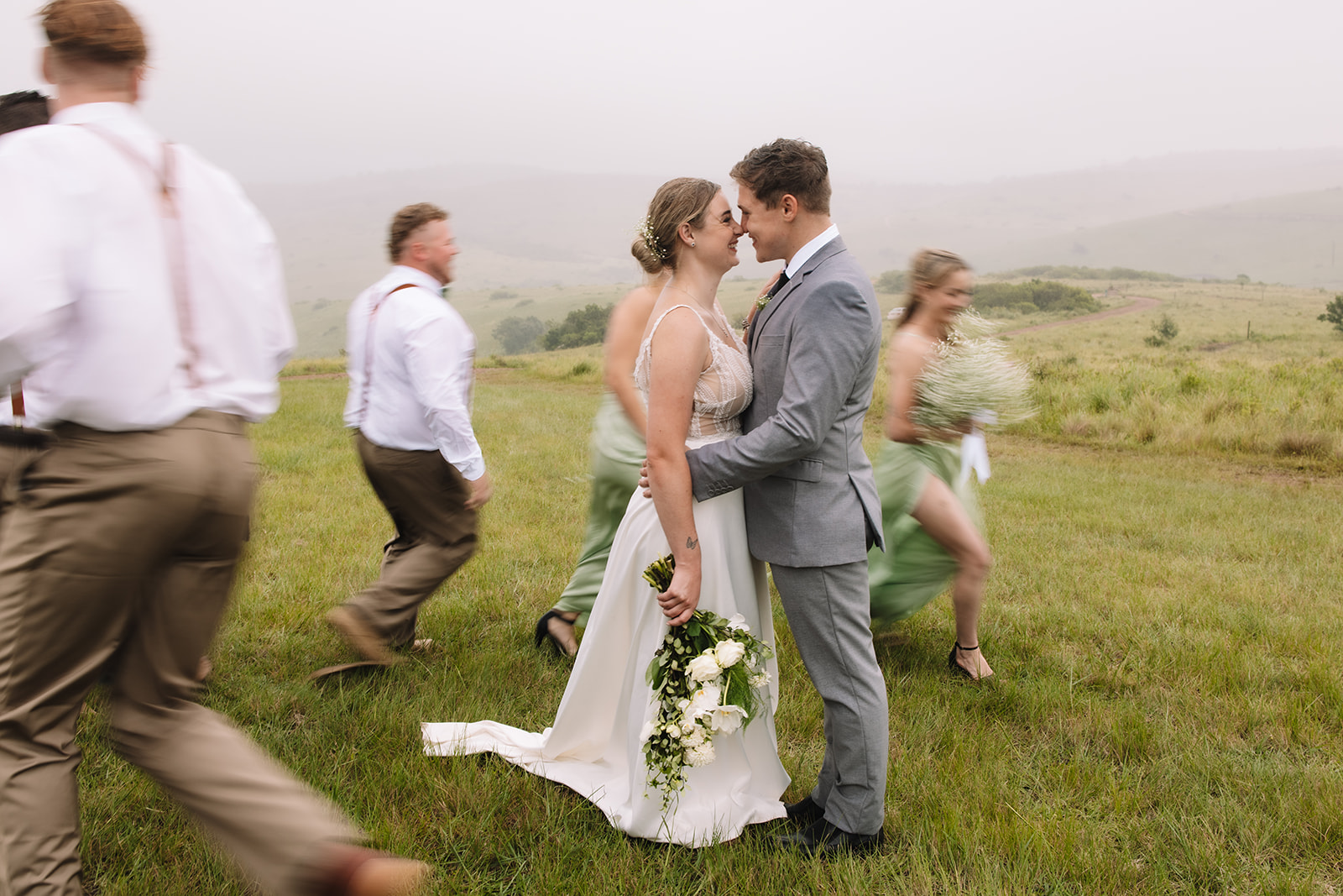 Bride and groom smiling as their bridal party runs around them during their destination wedding in South Africa