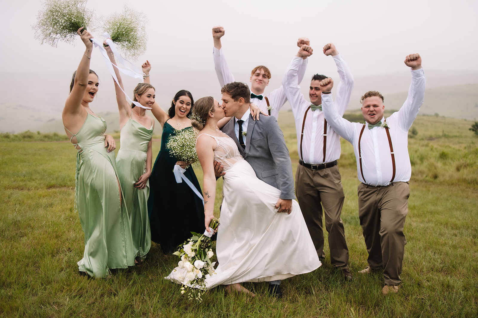 Bride and groom kissing as their bridal party cheers