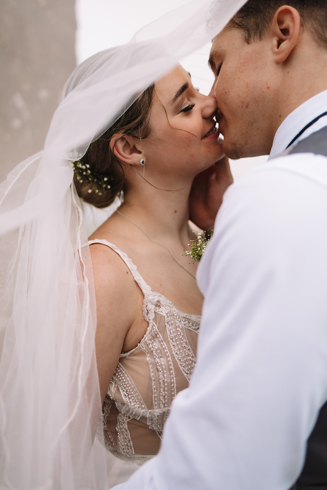 Bride and groom kissing under brides veil