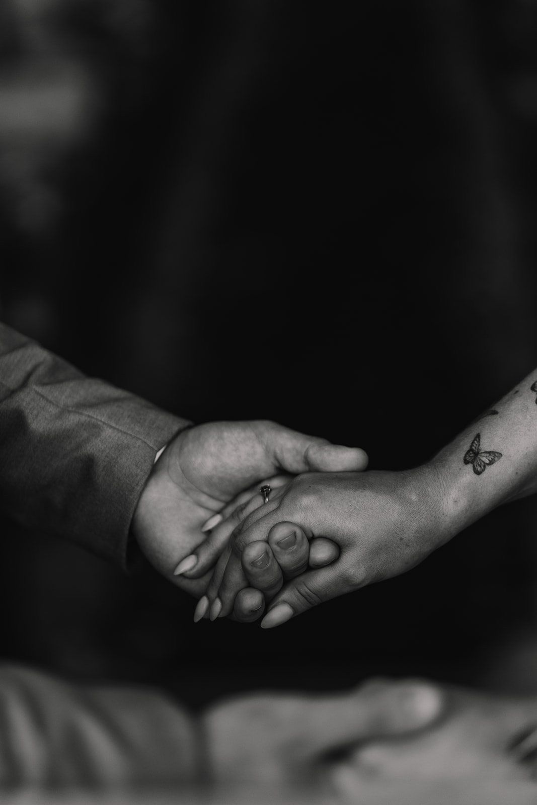 Black and white photo of bride and groom holding hands during their wedding ceremony