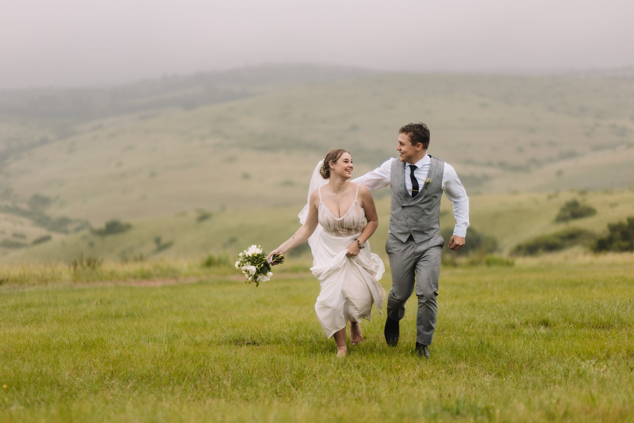 Bride and groom running in a field of grass during their destination wedding in South Africa