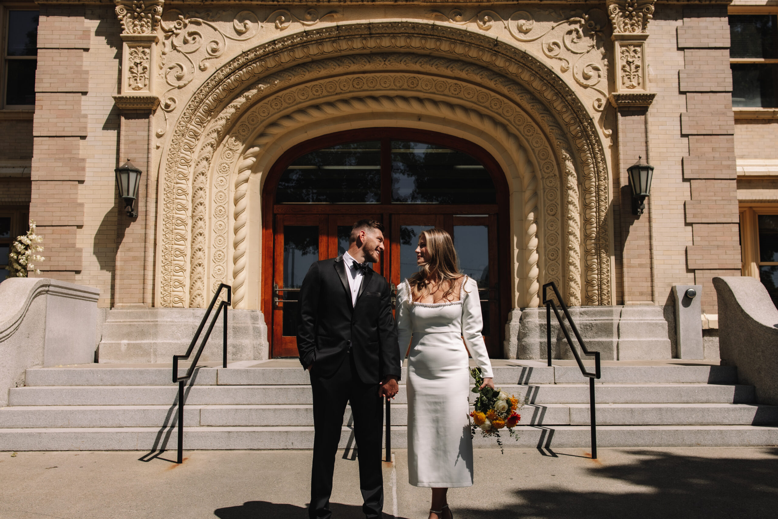 Bride and groom walking down the stairs in front of a courthouse after getting married 