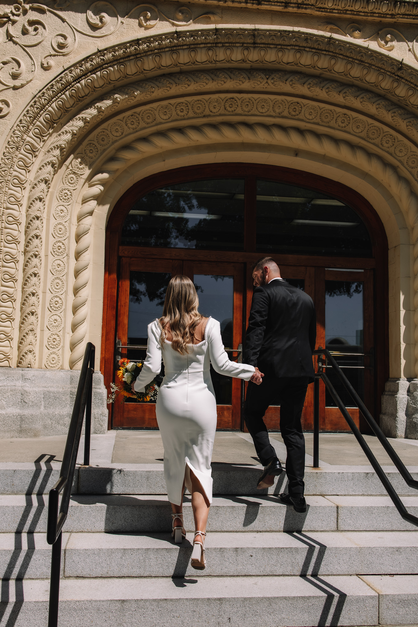 Courthouse wedding couple walking up the stairs towards the courthouse to get married