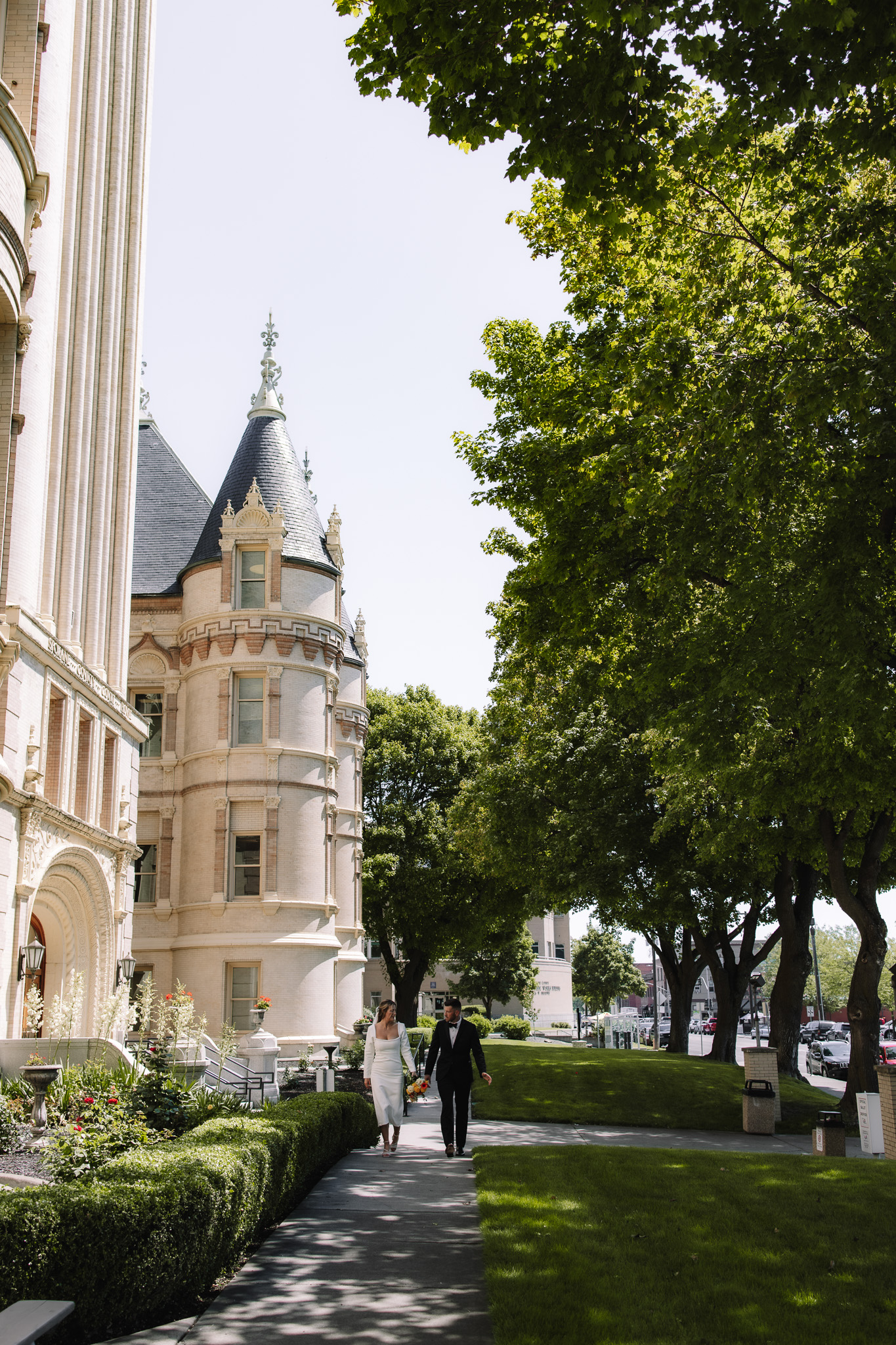 Wedding couple walking together next to a beautiful castle like courthouse