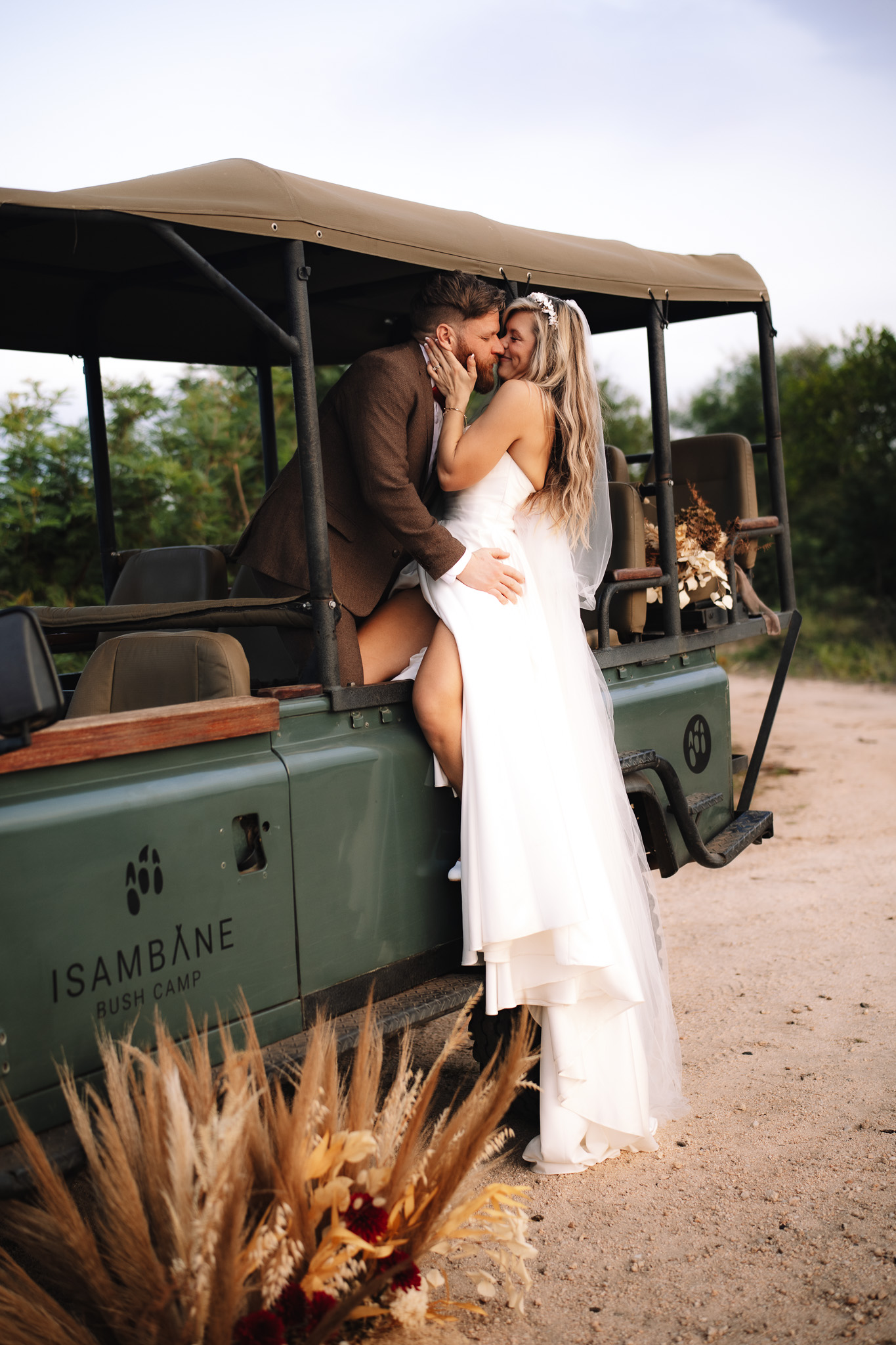 Bride and groom making out in the safari vehicle 