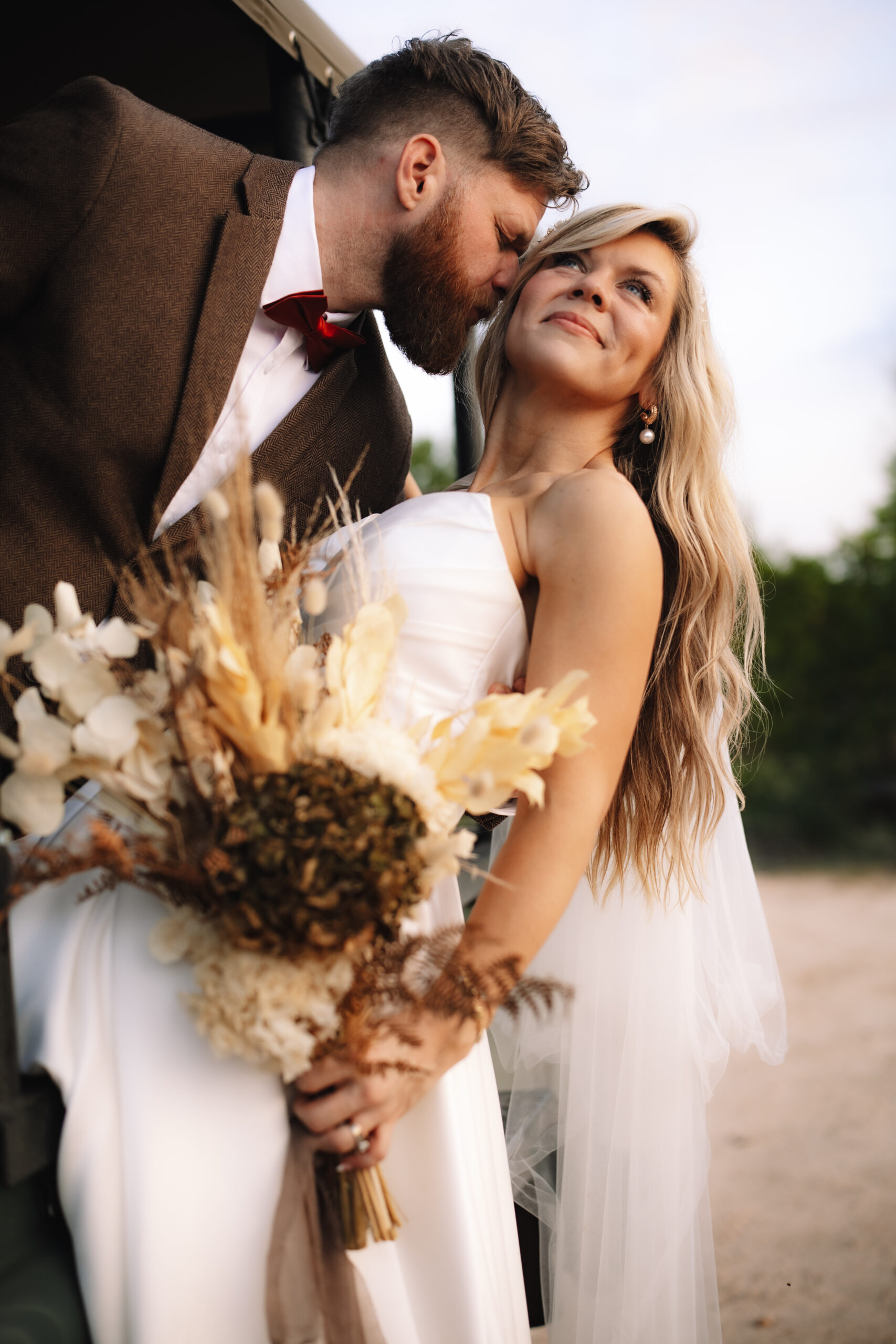 Bride leaning out of the safari vehicle while groom kisses her cheek during their safari wedding in South Africa