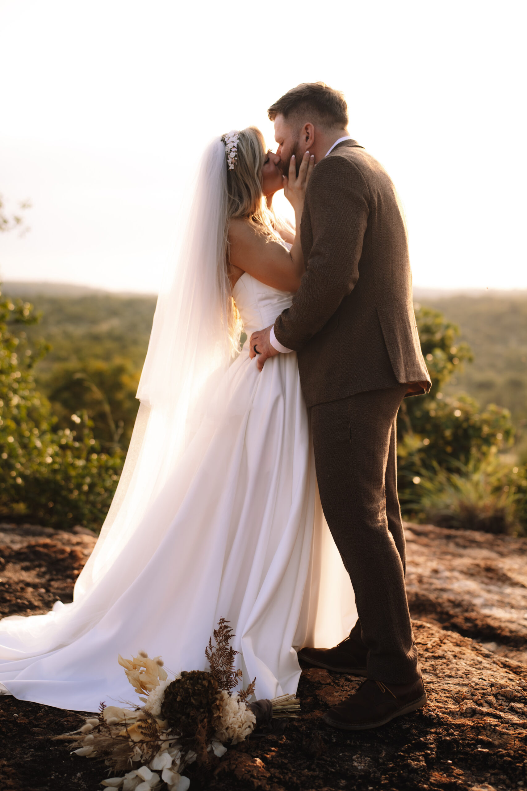 Bride and Groom kissing at the edge of a cliff overlooking the South African bush during their intimate safari wedding