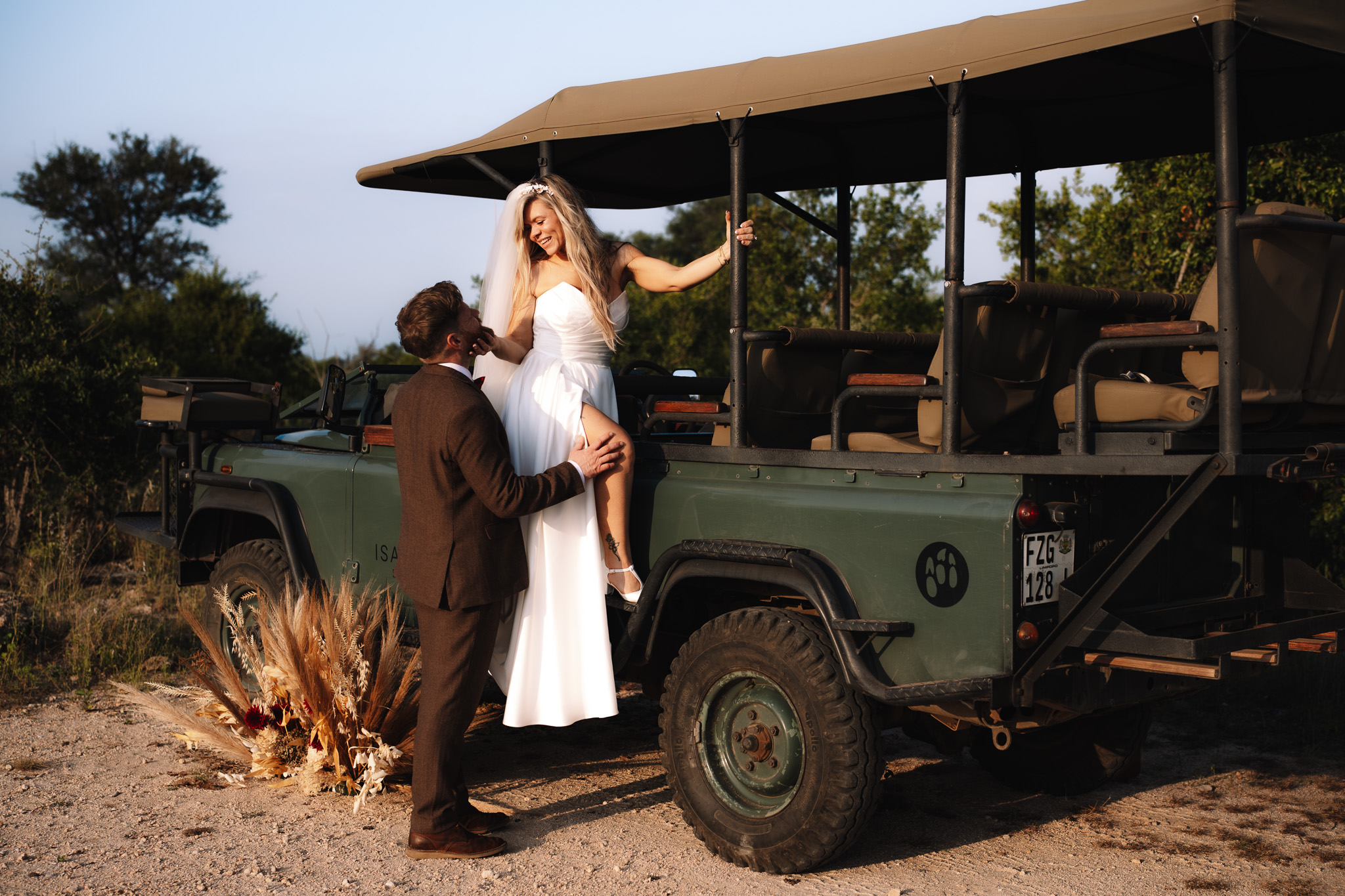 Bride leaning out of the safari vehicle while groom kisses her cheek during their safari wedding in South Africa