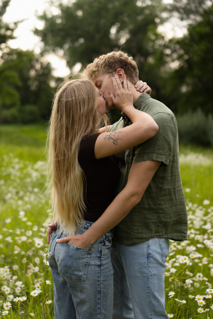 Engagement couple kissing in a field of daisies at Lake Minnewashta Regional park