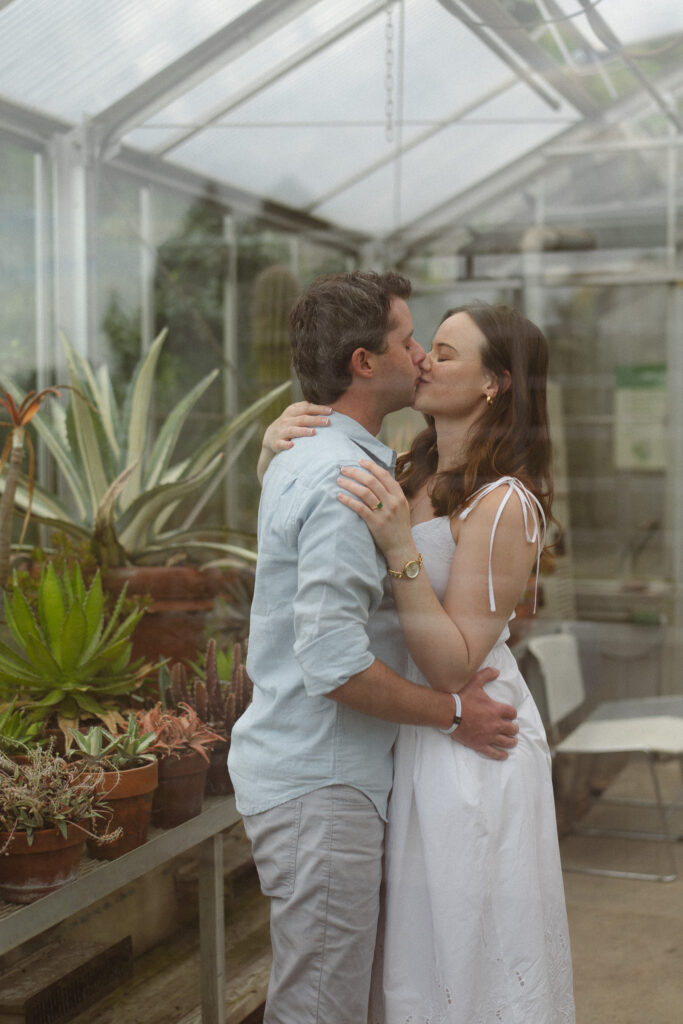 Engagement couple kissing inside a green house during their engagement photos at the Minnesota Landscape Arboretum