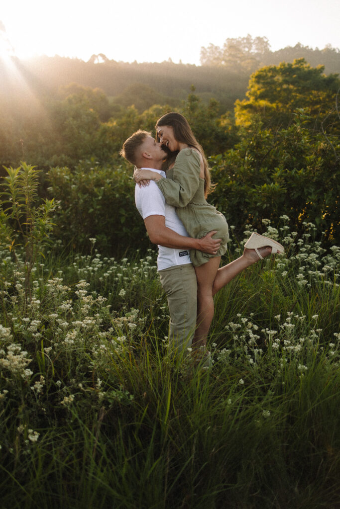 Guy picking up his girl during their engagement session at the Minnesota Landscape Arboretum in Chaska- one of the best engagement photo locations in Minneapolis' west suburbs
