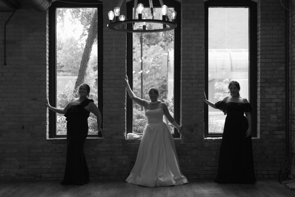 Bride and her bridesmaids posing in front of the tall windows located inside The View Wedding venue in St Anthony Main