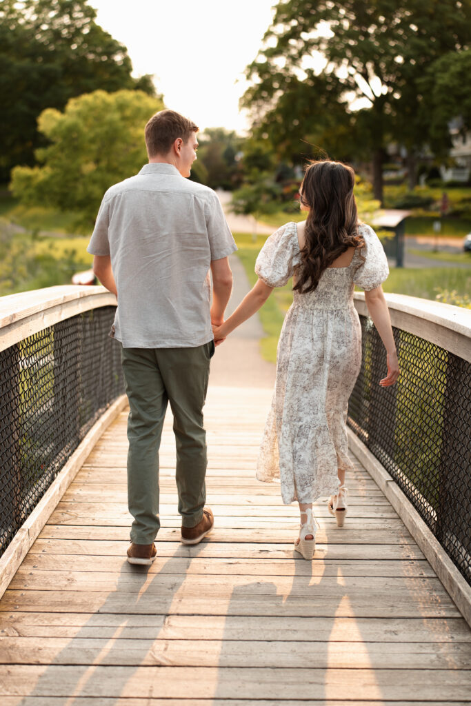 Engagement couple walking over a bridge in Wayzata during sunset
