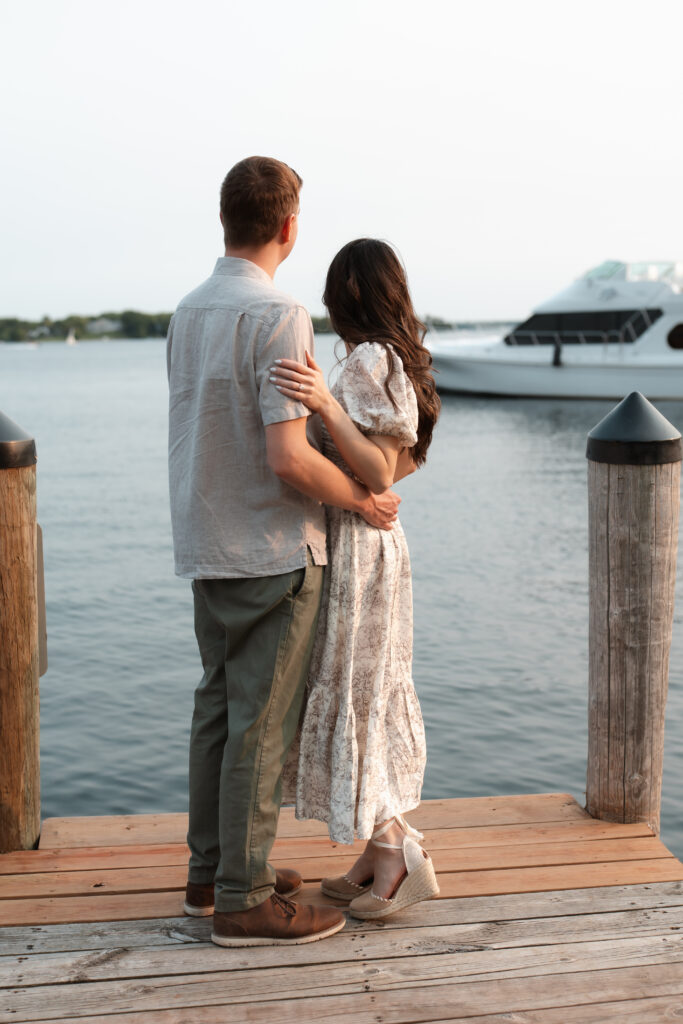 Engagement couple standing on the docks overlooking lake Minnetonka during their Wayzata engagement session