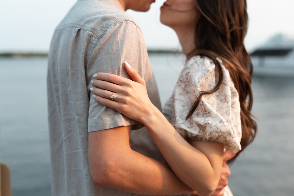 Engagement couple going in for a kiss while standing on the docks in Wayzta