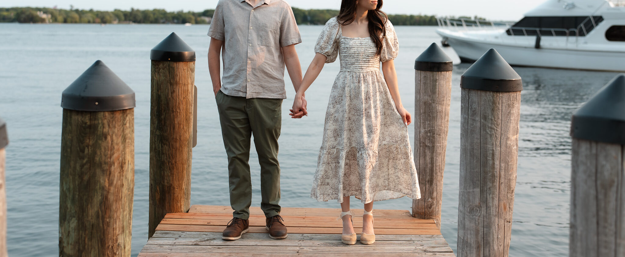 Engagement couple standing side by side, facing opposite directions while standing on the dock during their Wayzata engagement photos