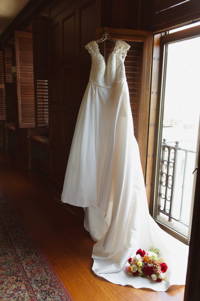 Beautiful timeless wedding dress hanging next to a door at The Women's Club in Minneapolis