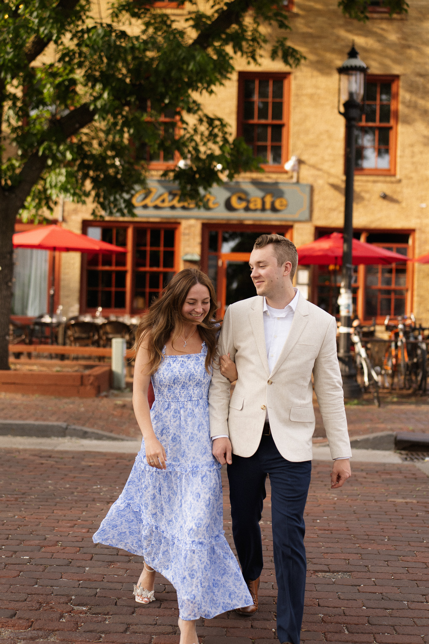 Minneapolis Engagement couple walking hand in hand along the cobblestone stone street across from Aster Cafe