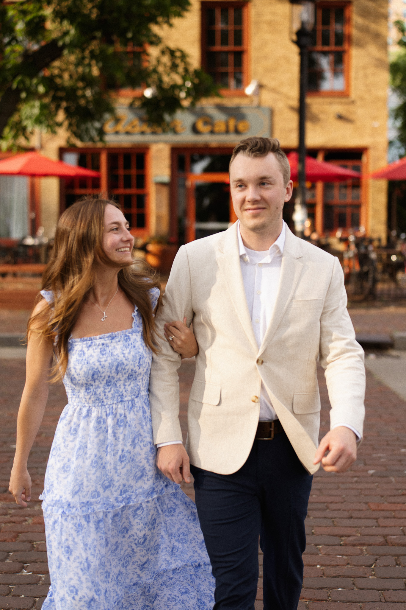 Minneapolis Engagement couple walking hand in hand along the cobblestone stone street across from Aster Cafe