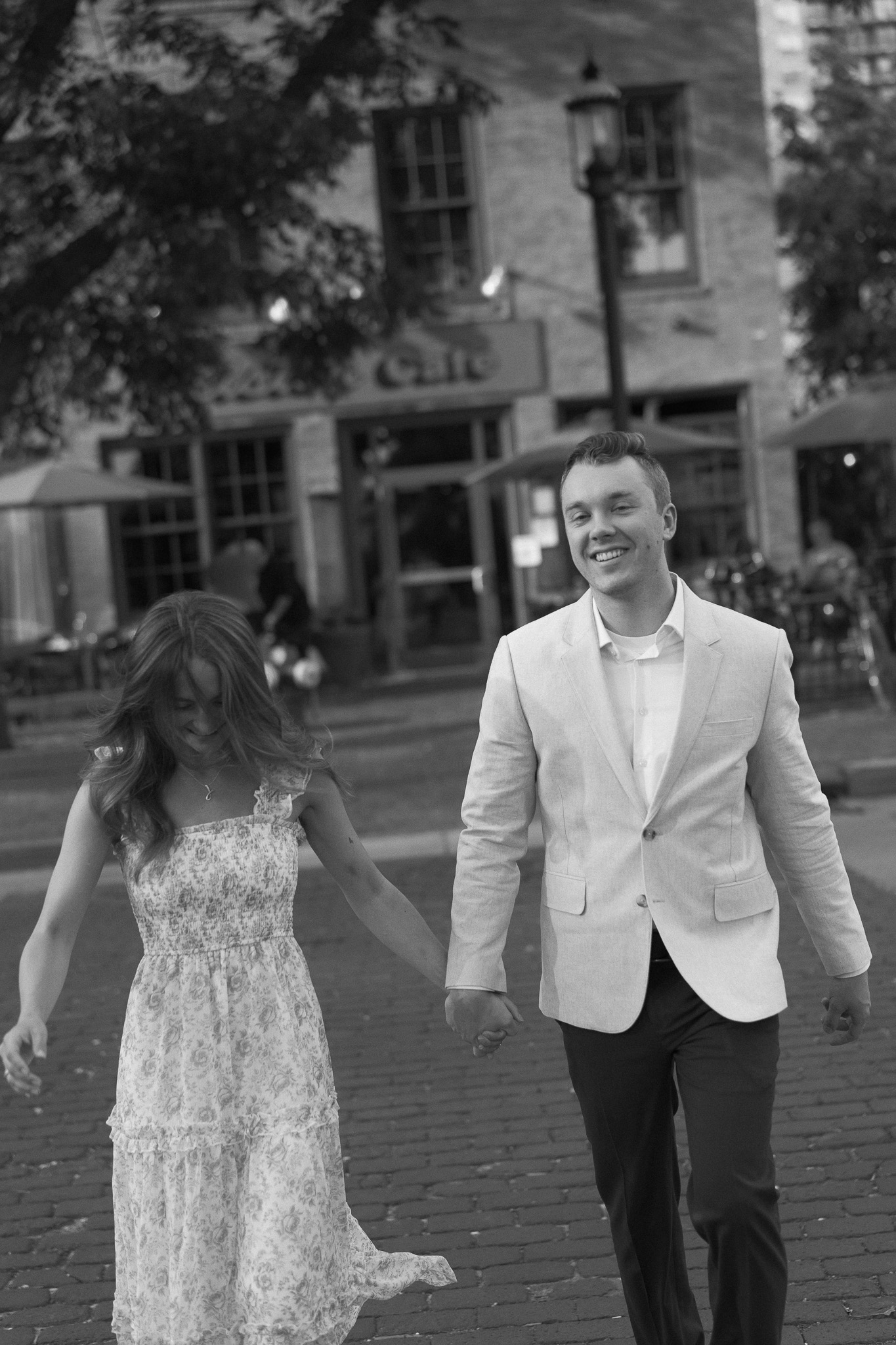 Minneapolis Engagement couple walking hand in hand along the cobblestone stone street across from Aster Cafe