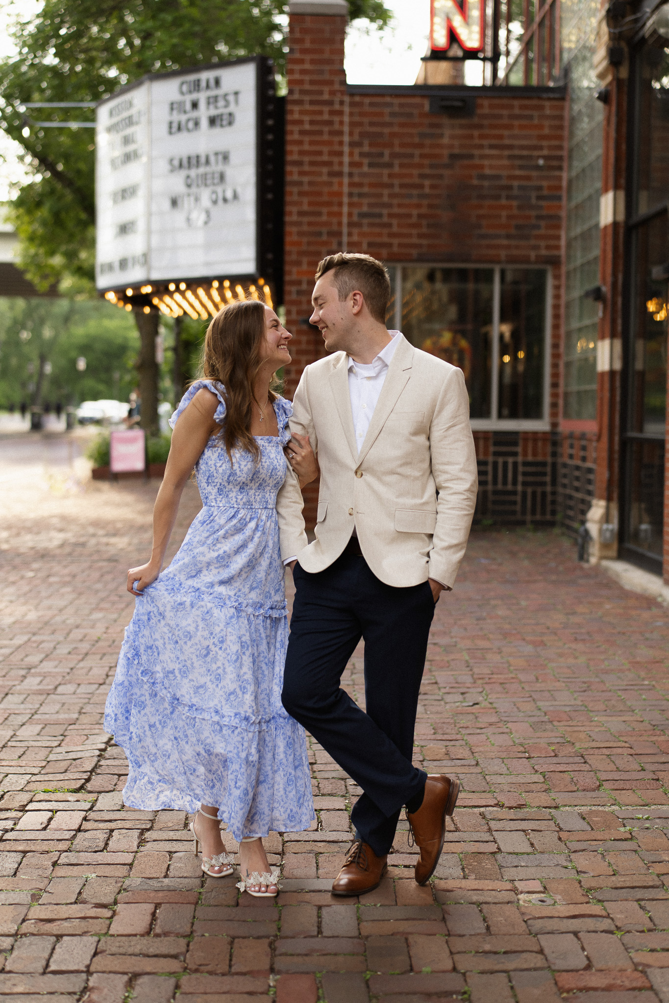 Engagement couple standing in front of the St Anthony Main Theatre with string lights handing in the background