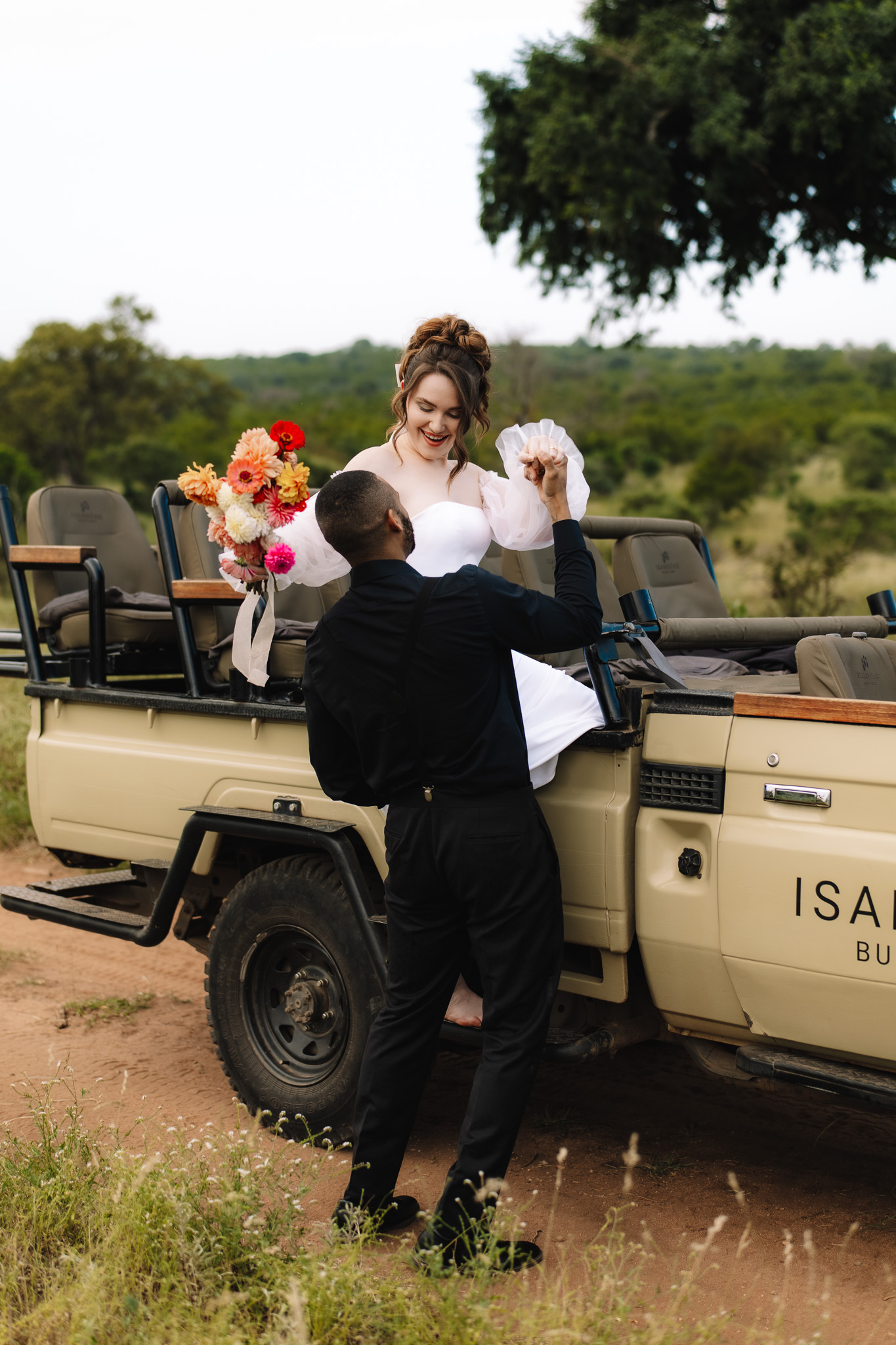 Groom helping his Bride climb out of the safari vehicle