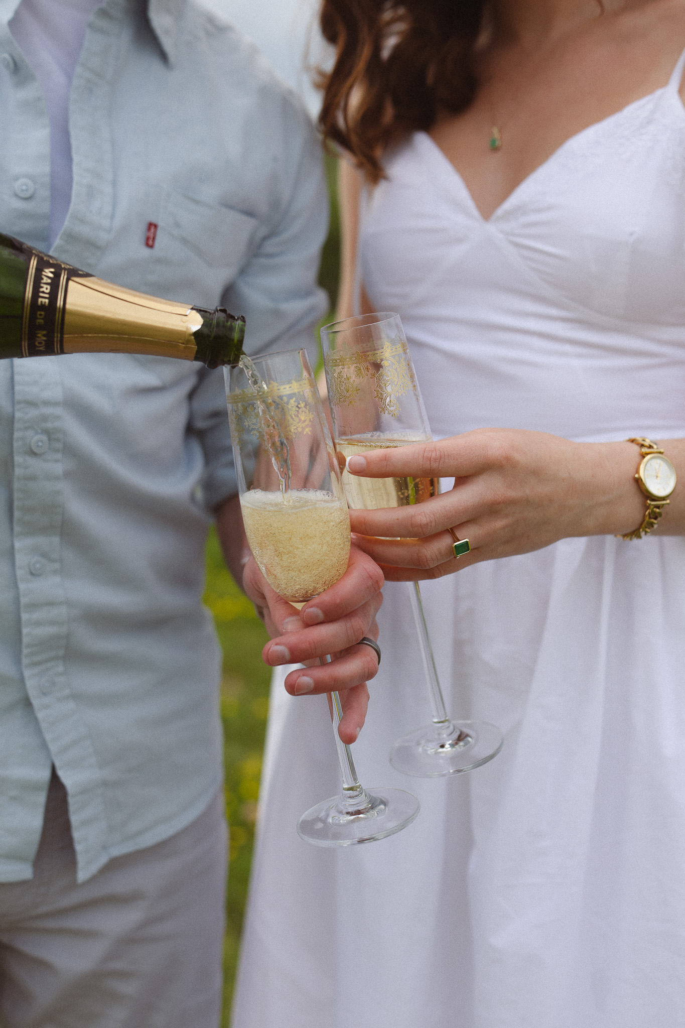 Close up shot of an engagement couple pouring champagne into their glasses during their engagement session in Chaska, MN