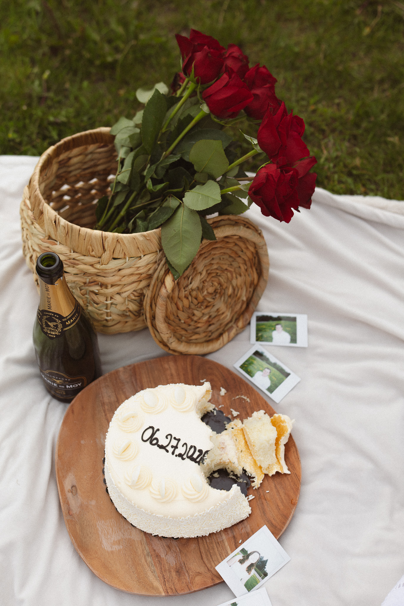 Flat lay detail shot of a picnic blanket with a cake, flowers in a basket and champagne