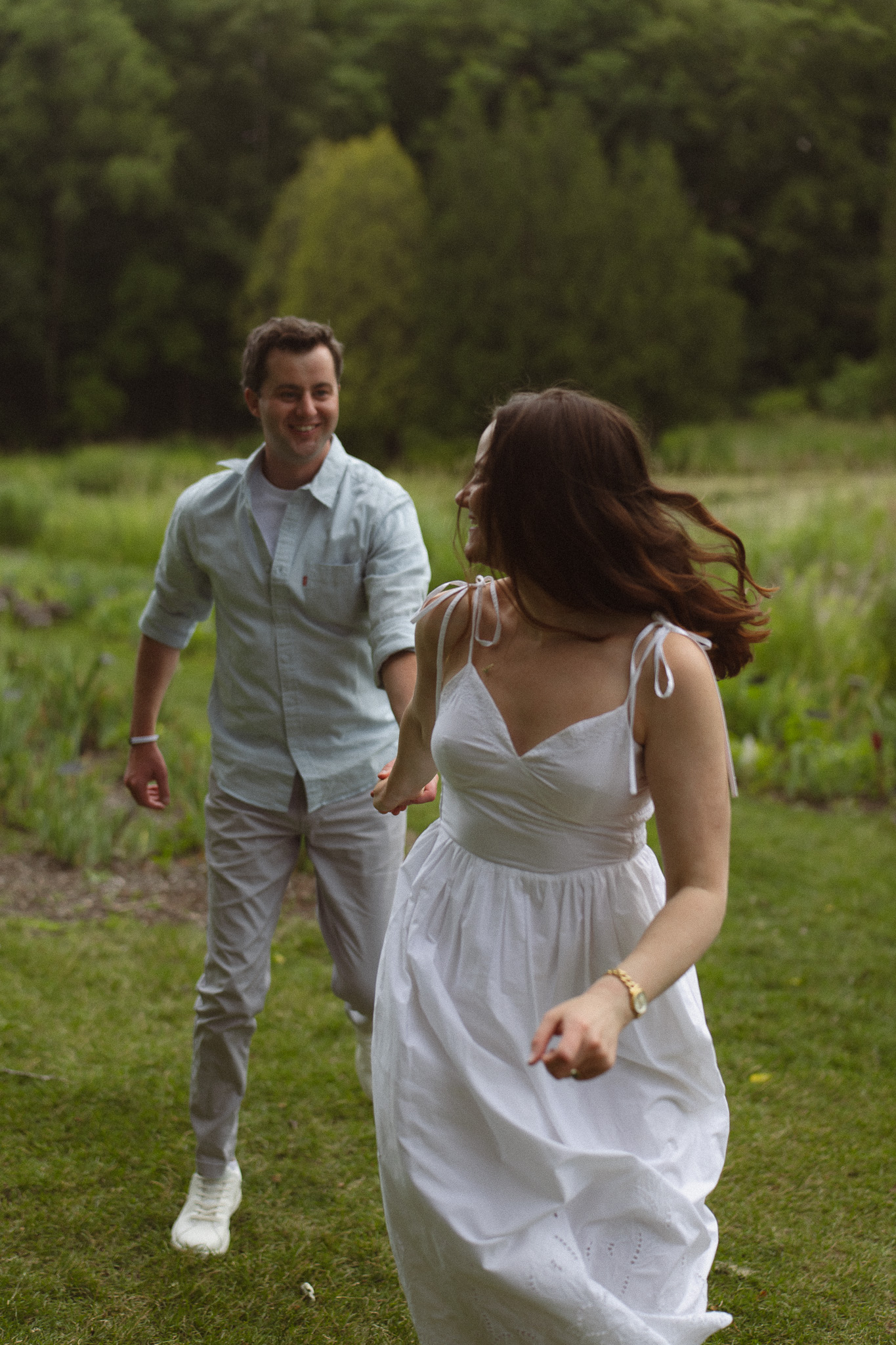 Engagement couple running together on grass at the Minnesota Landscape Arboretum