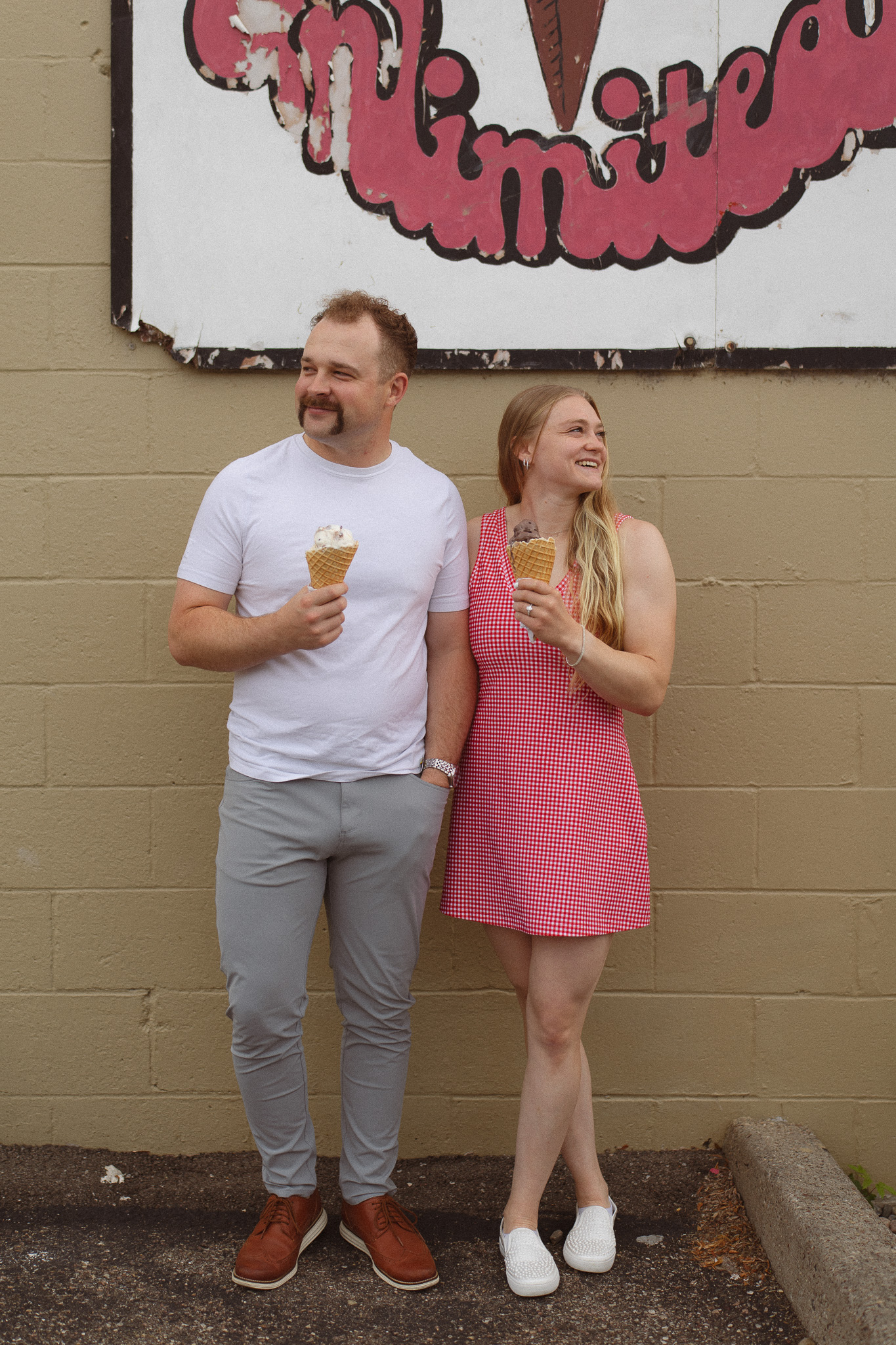 Playful engagement photo of a couple sharing ice cream at Lick’s in downtown Excelsior.