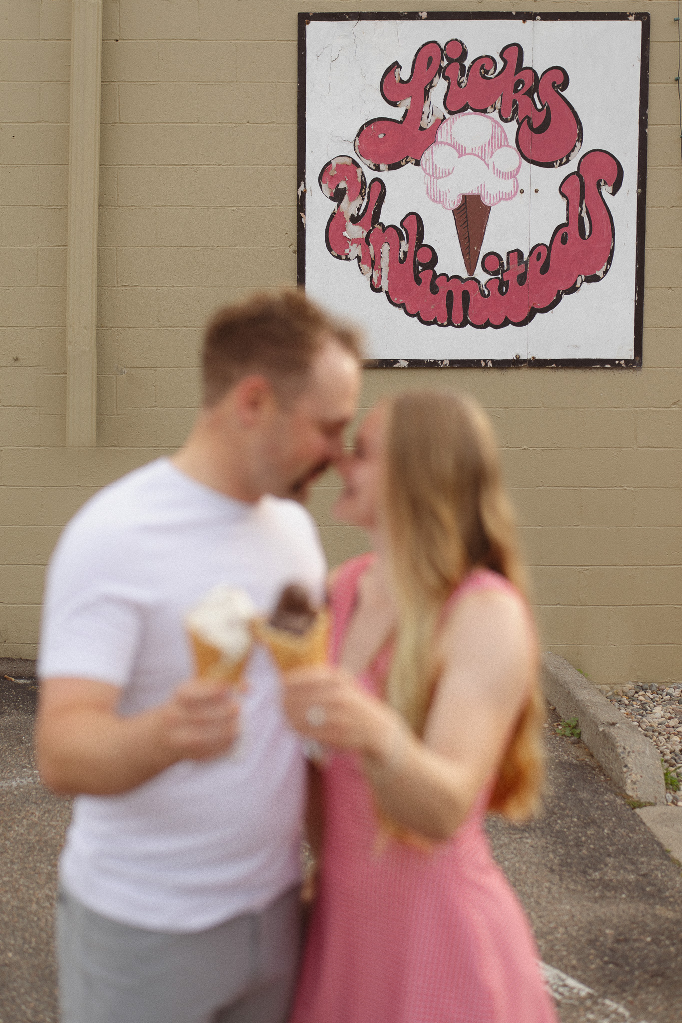 Playful engagement photo of a couple sharing ice cream at Lick’s in downtown Excelsior.