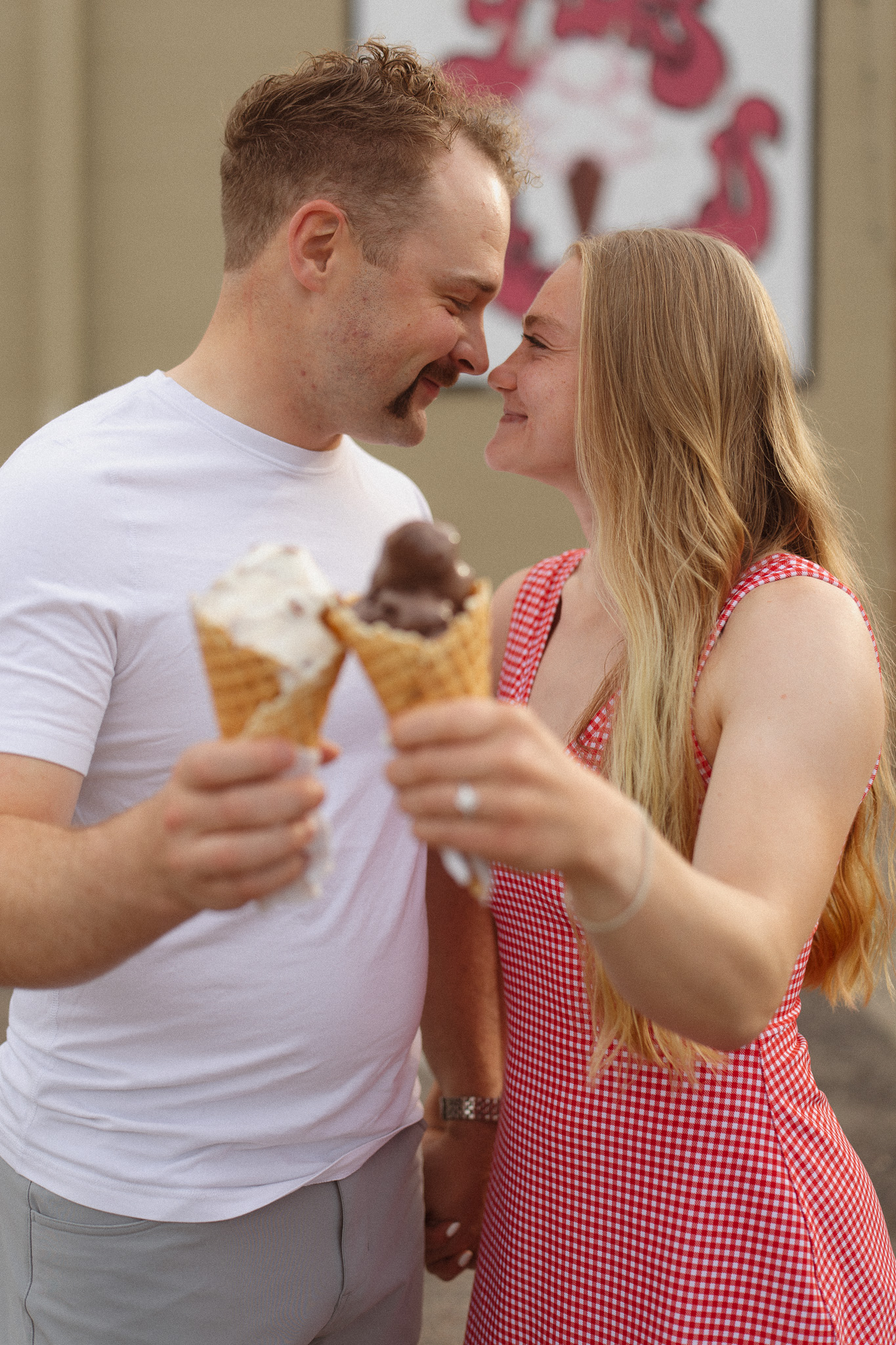 Playful engagement photo of a couple sharing ice cream at Lick’s in downtown Excelsior.